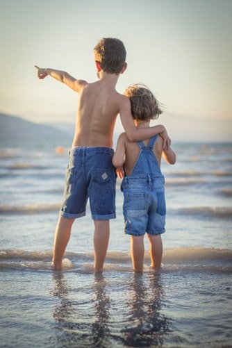 Deux enfants debout sur la plage | Photo : Pixabay