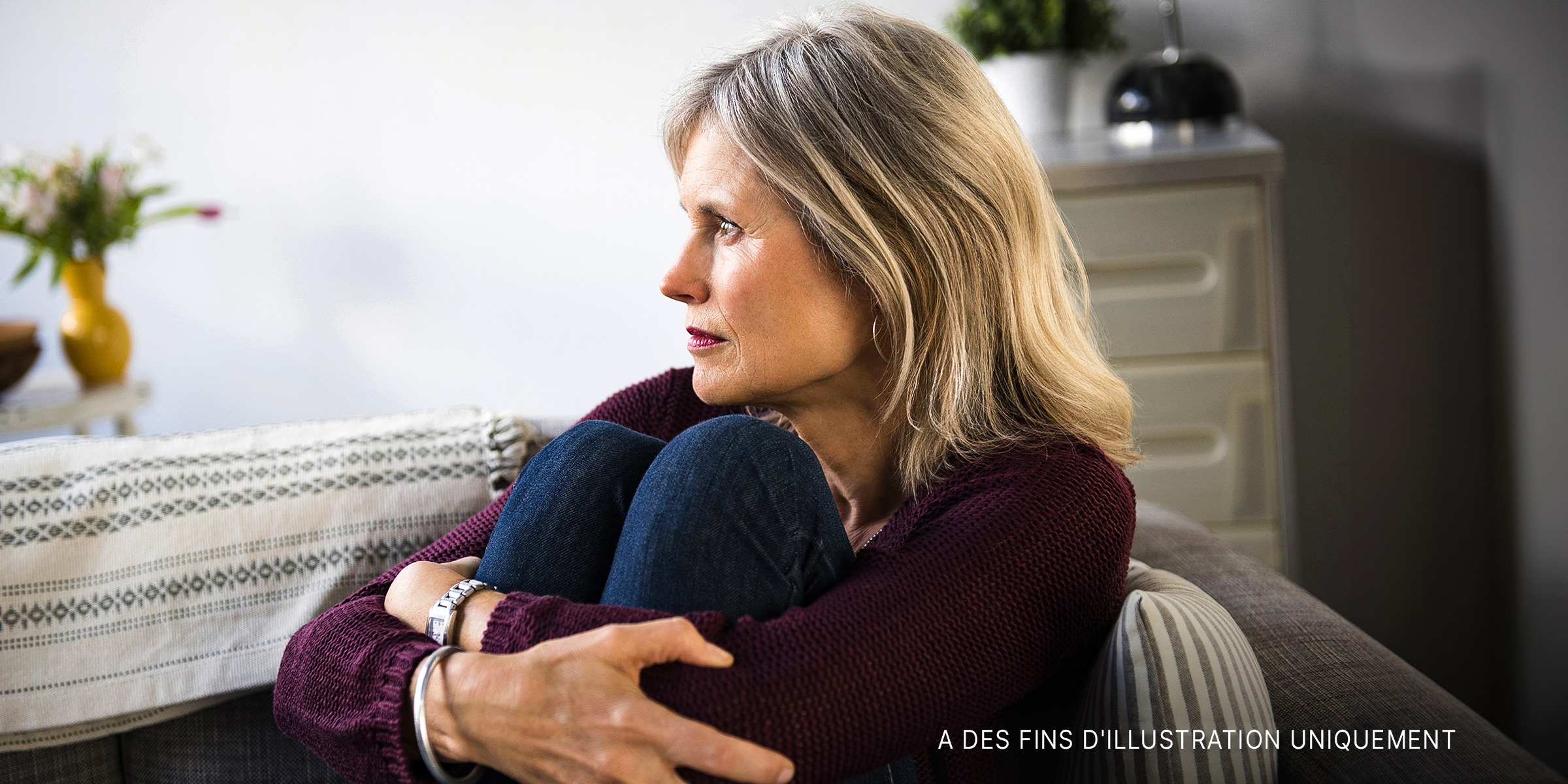 Une femme assise sur le canapé, l'air triste | Source : Shutterstock