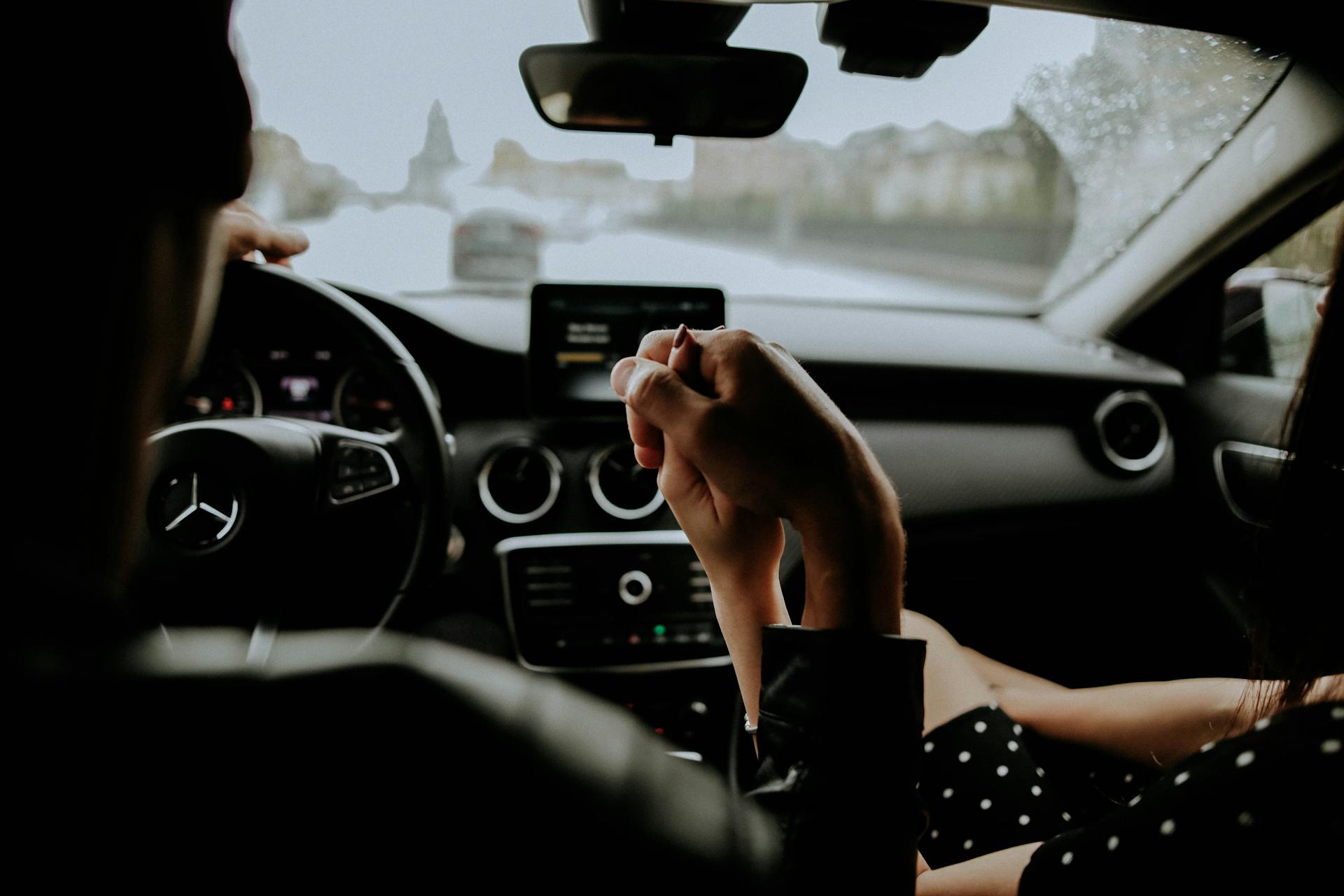 Un couple se tenant par la main à l'intérieur d'une voiture | Source : Pexels