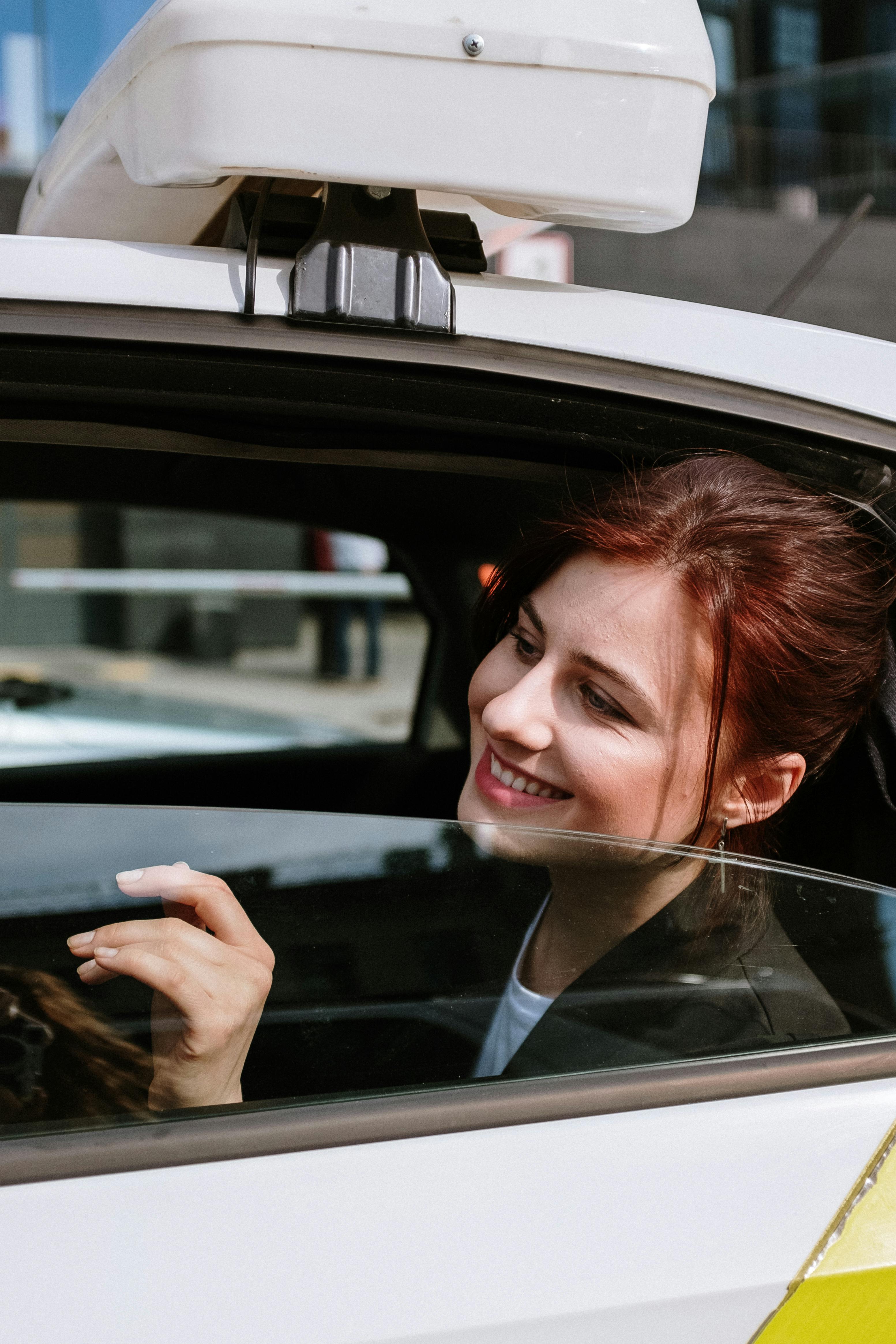 Une femme souriante qui regarde par la fenêtre d'une voiture | Source : Pexels