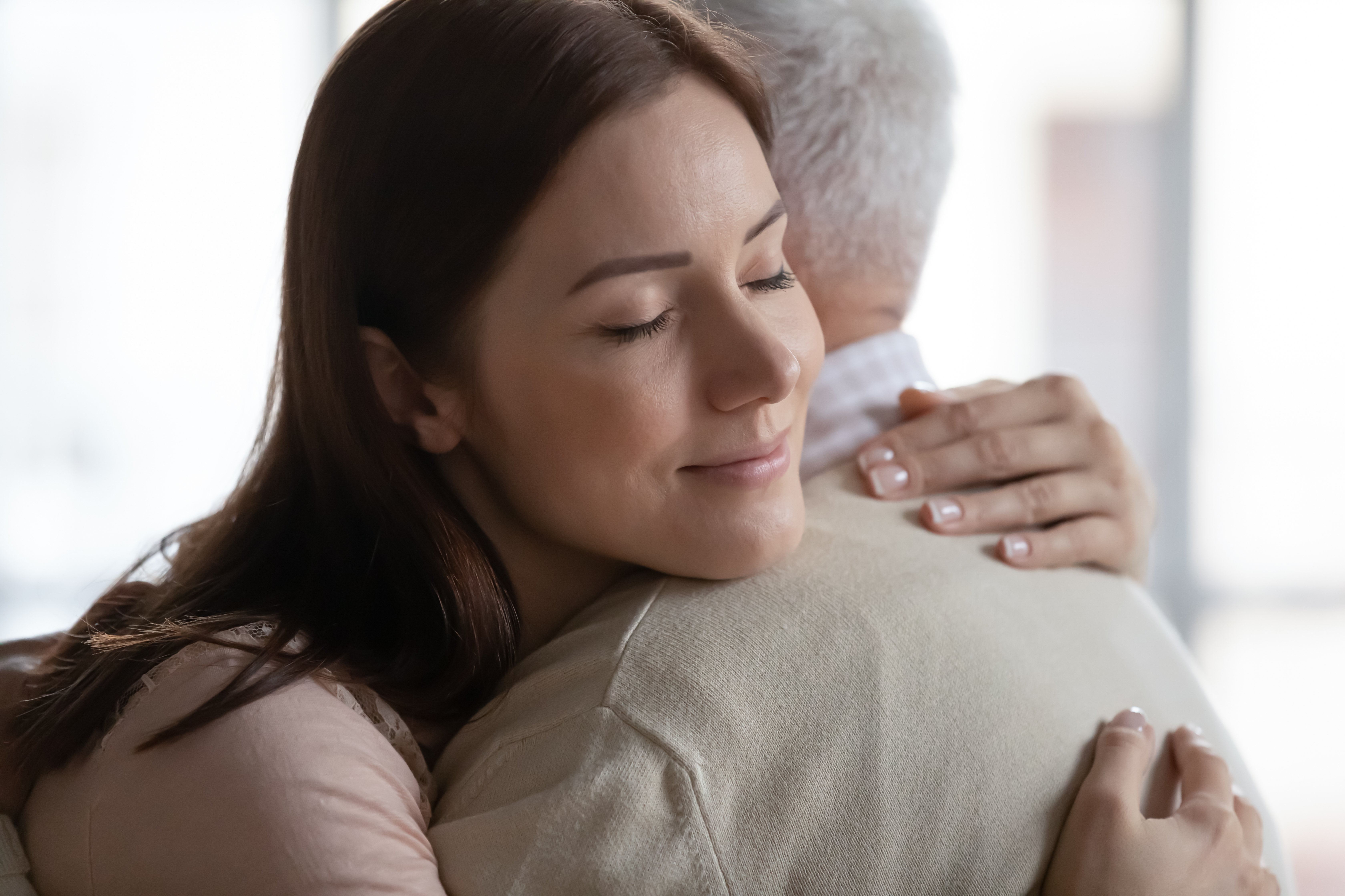 Une jeune femme serrant son père âgé dans ses bras | Source : Shutterstock
