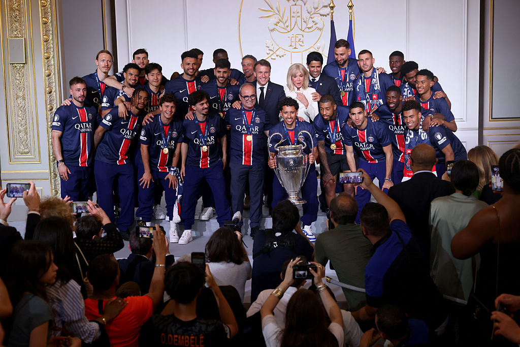 Le président français Emmanuel Macron, son épouse Brigitte Macron, les joueurs et le staff du Paris Saint-Germain posent pour une photo avec le trophée lors de la réception au palais présidentiel de l'Élysée à Paris, le 1er juin 2025, au lendemain de la victoire du PSG en finale de la Ligue des champions de l'UEFA 2025 contre l'Inter Milan à Munich. | Source : Getty Images