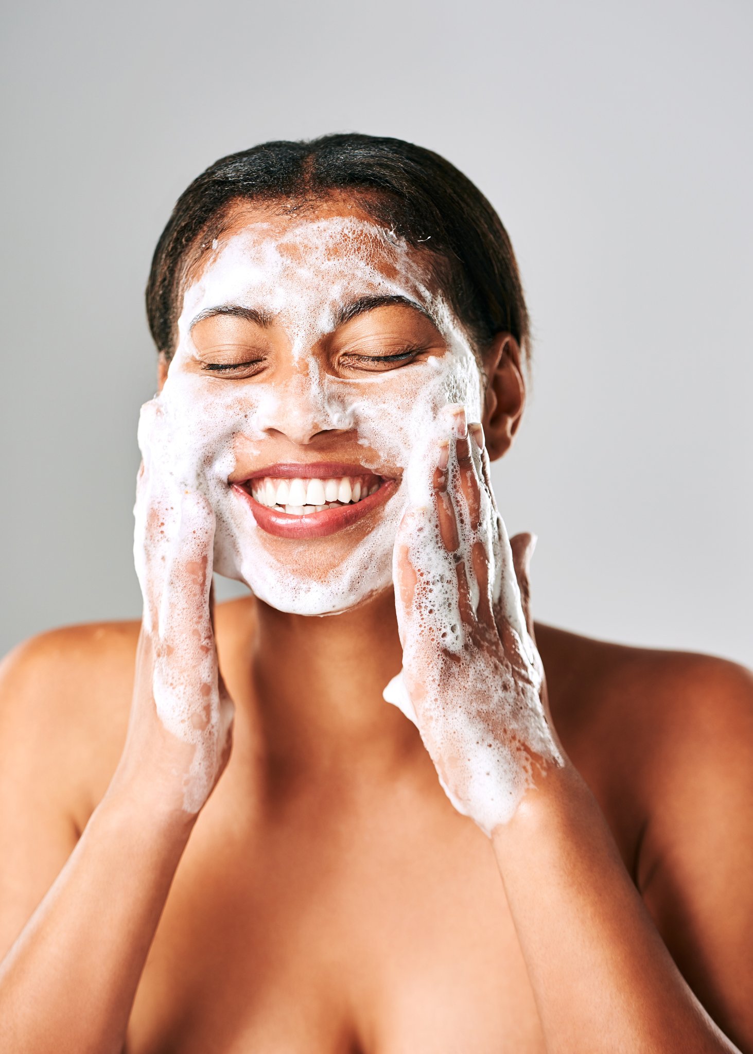 Photo d'une jeune femme se lavant le visage avec une mousse blanche | Source : Getty Images 