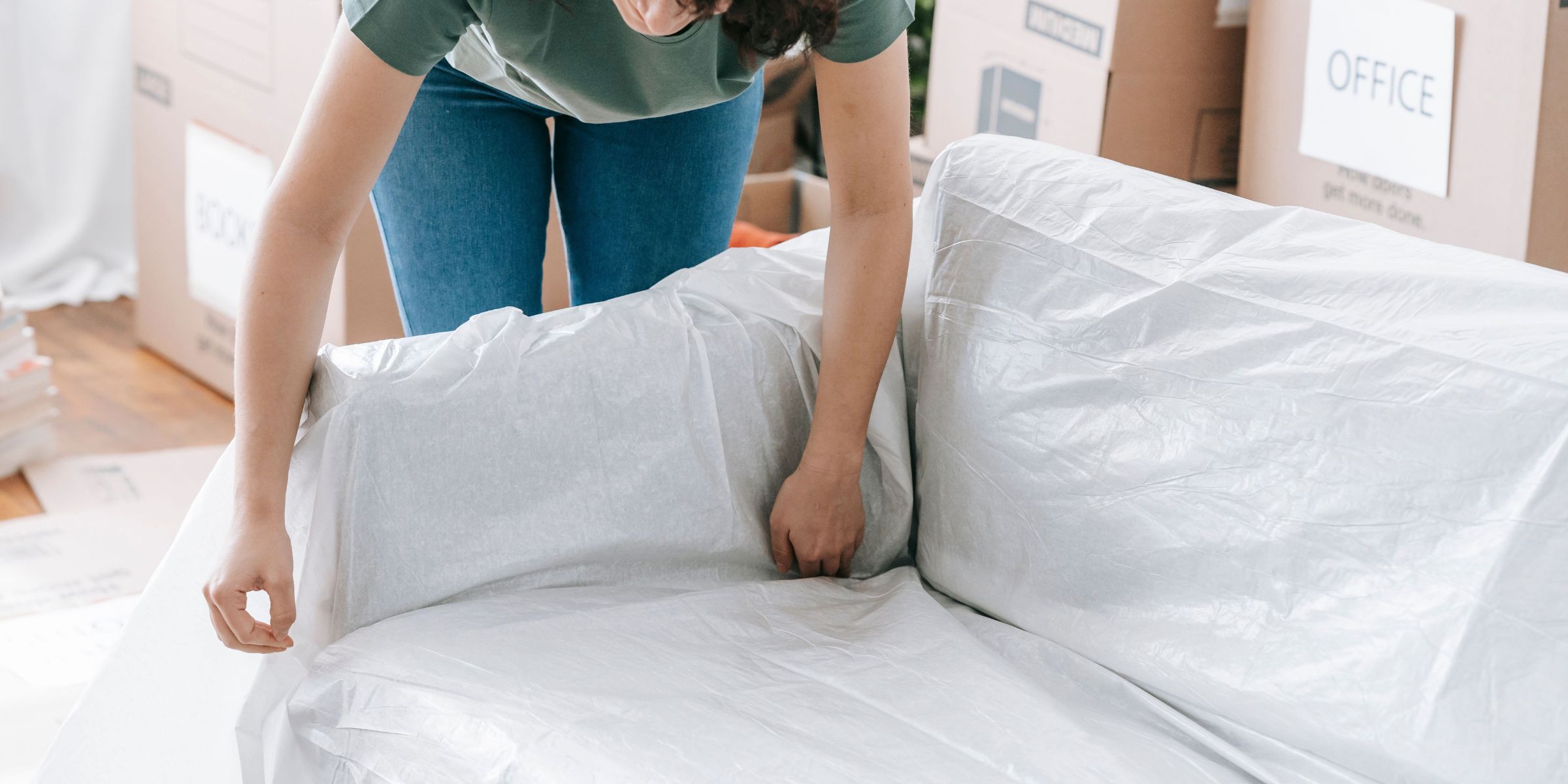 Une femme emballe soigneusement un canapé dans un matériau de protection | Source : Pexels