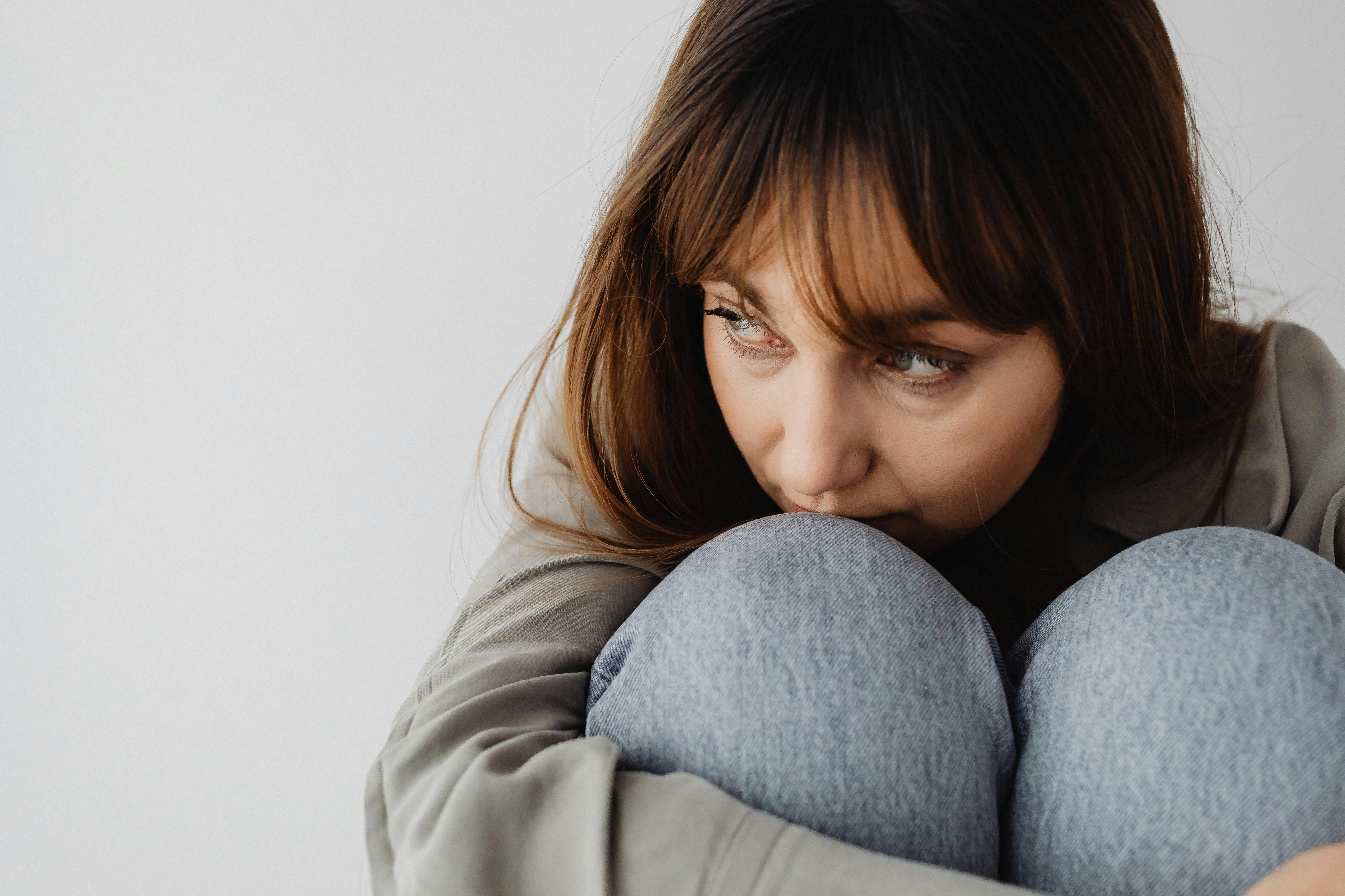 A sad and serious woman hugging her knees | Source: Pexels