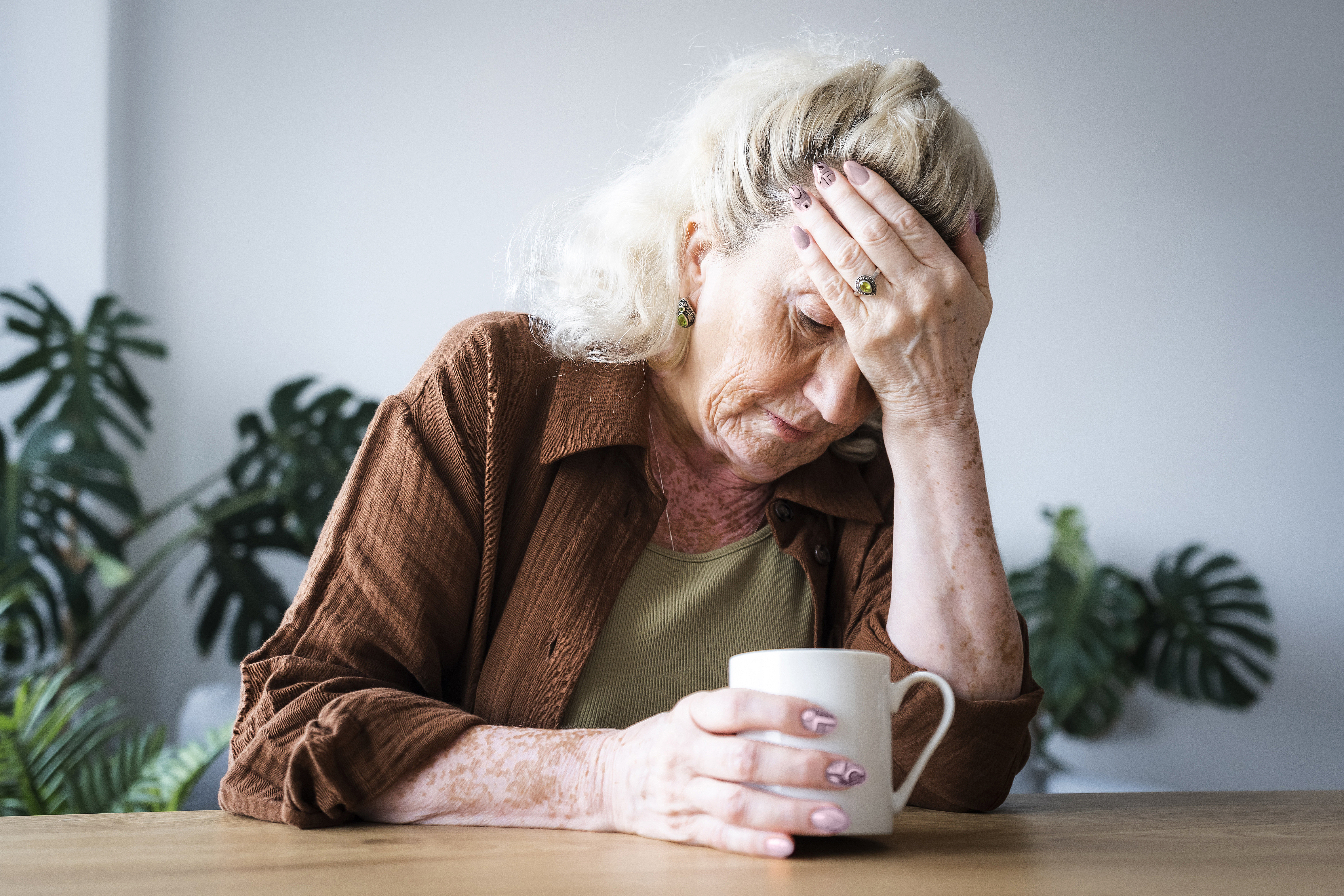 Une femme âgée bouleversée assise avec une boisson | Source : Getty Images