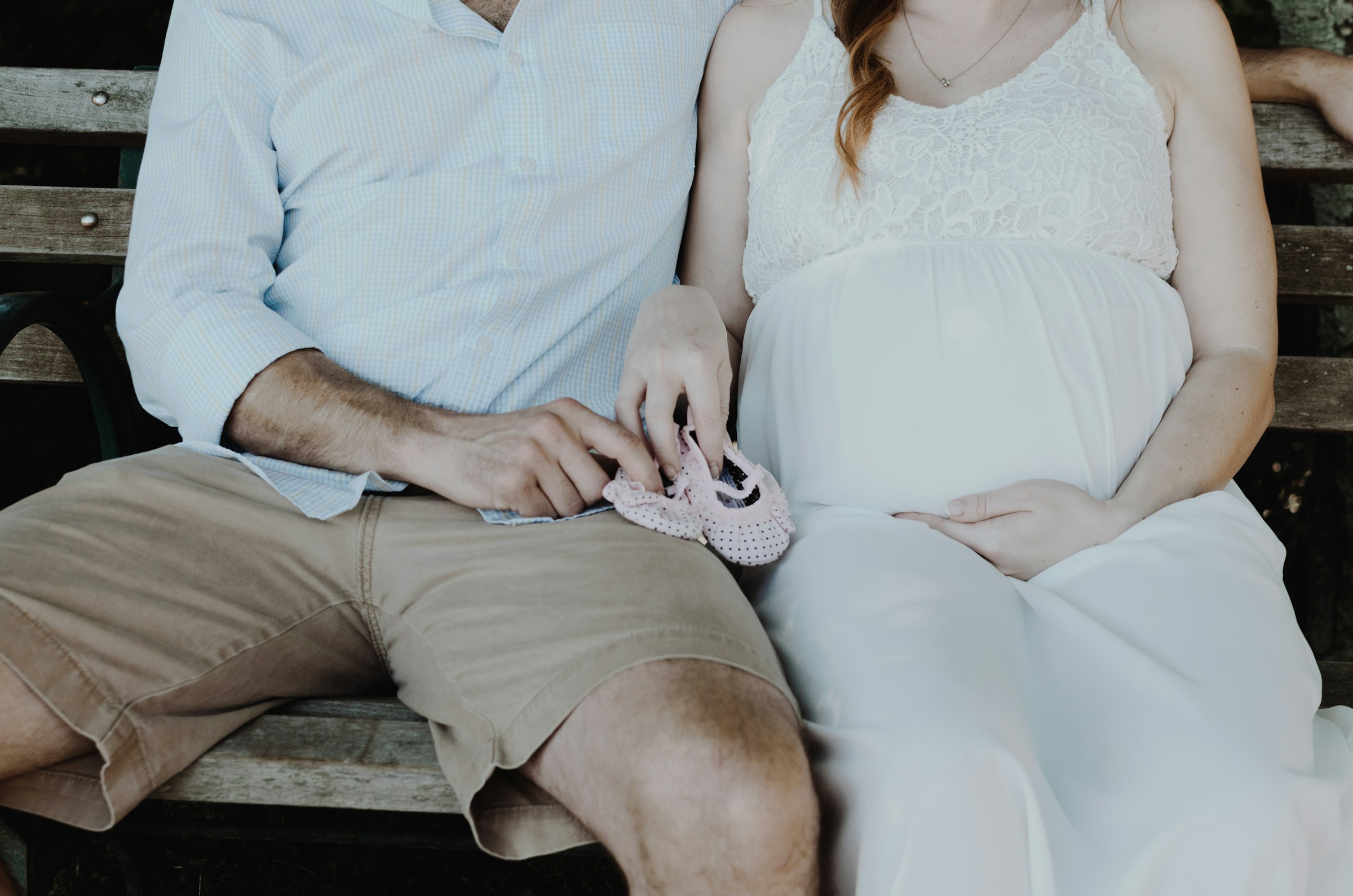 Un homme et une femme enceinte assis sur un banc en bois | Source : Unsplash