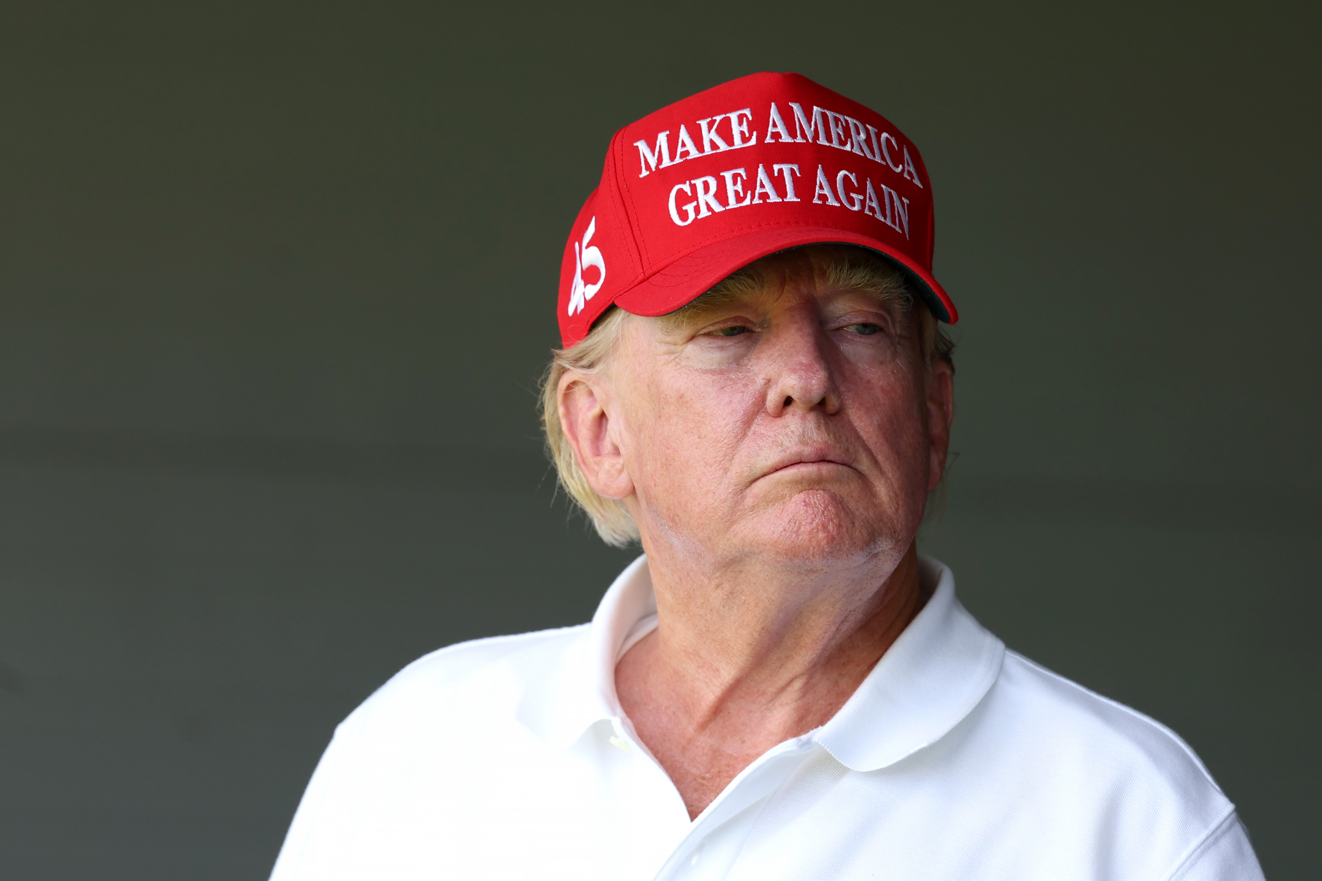Le 26 mai, Donald Trump regarde depuis une zone ombragée en portant le même chapeau rouge et la même chemise blanche. Son teint semble plus uniforme sous la lumière plus faible, bien que la coloration rouge soit encore forte près de ses joues.