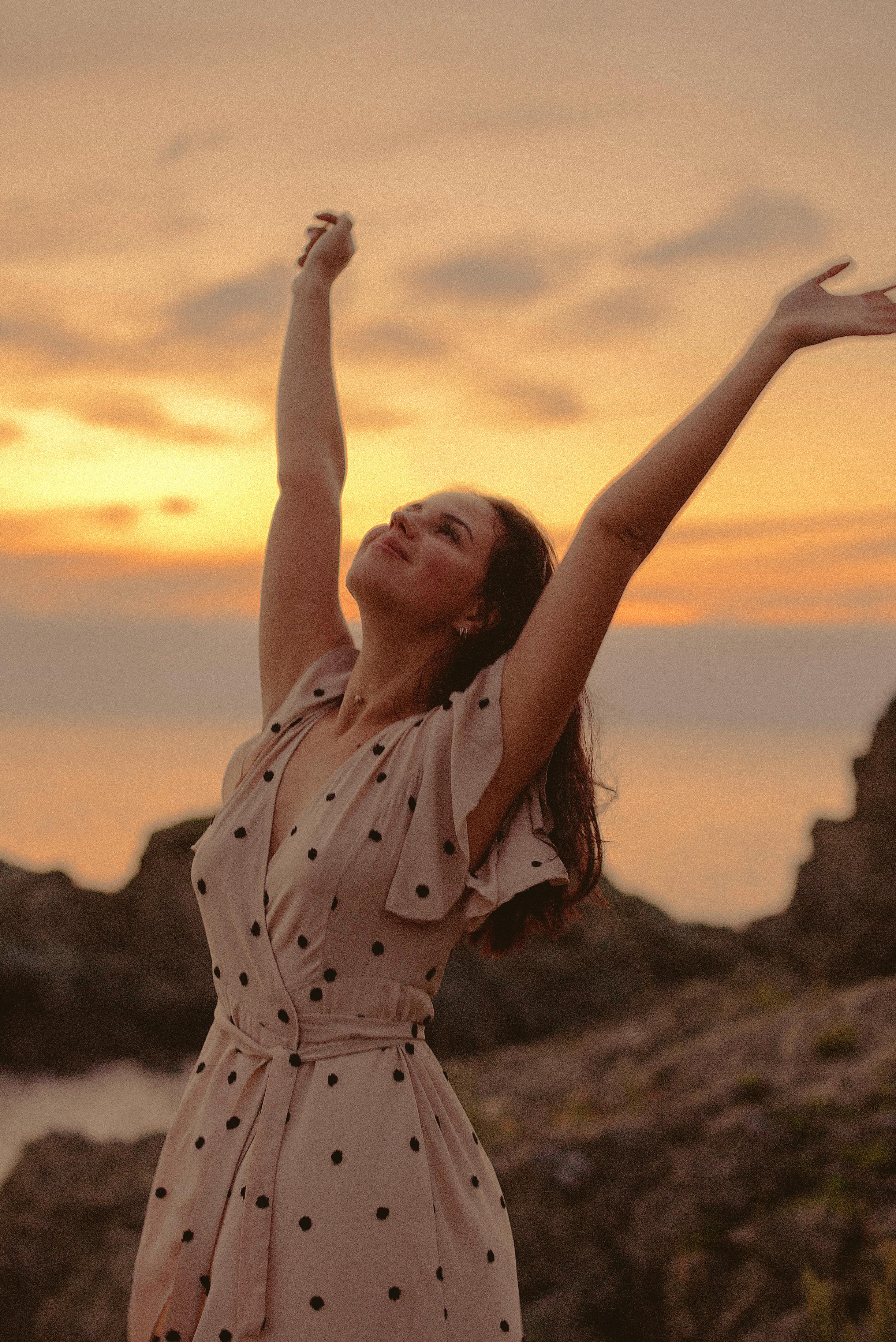 Une femme heureuse et reconnaissante qui regarde le ciel les bras tendus | Source : Pexels