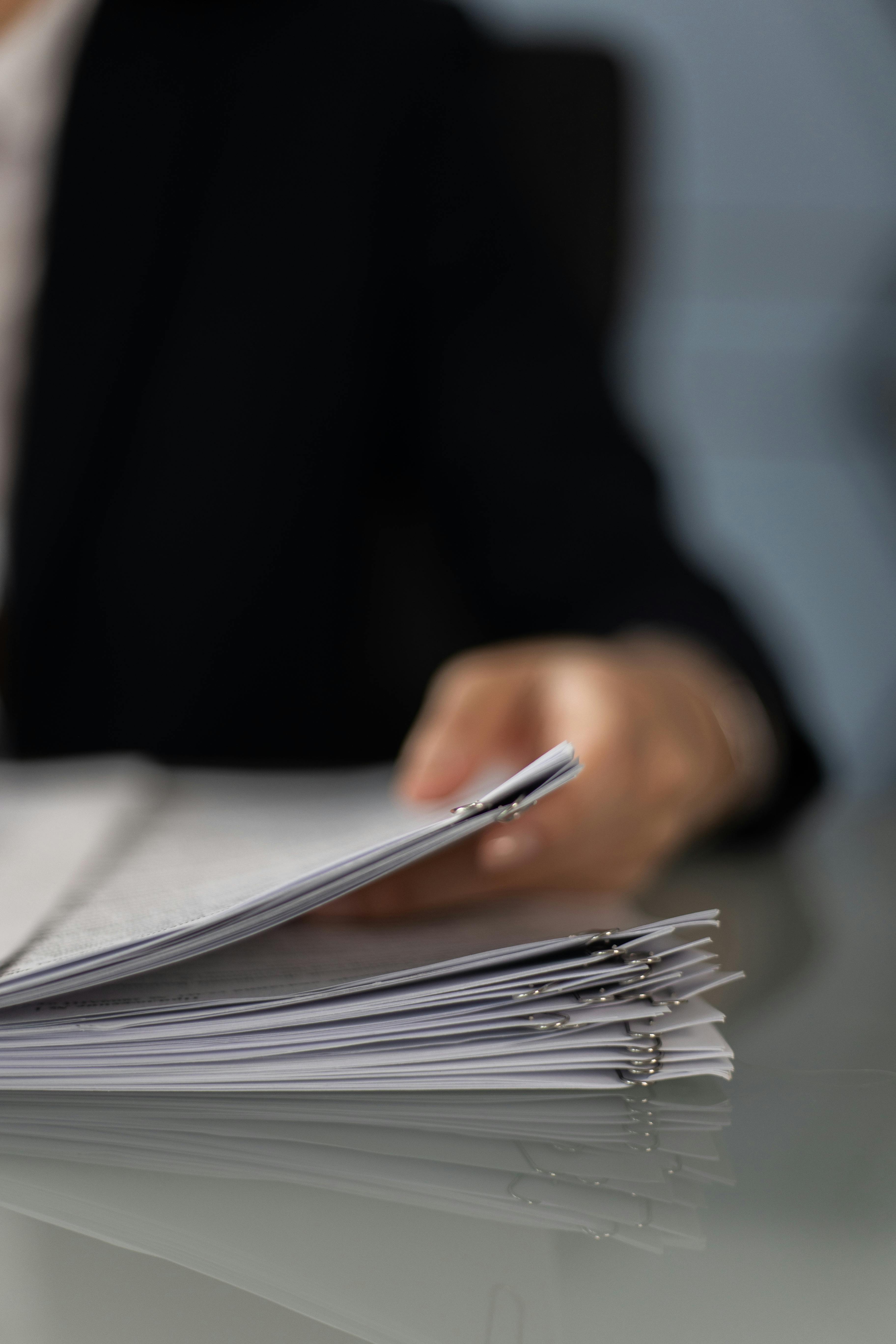 Gros plan d'une personne tenant des documents administratifs | Source : Pexels