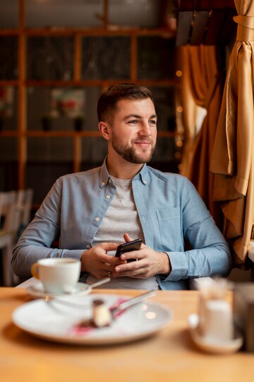 Un homme souriant dans un café | Source : Freepik