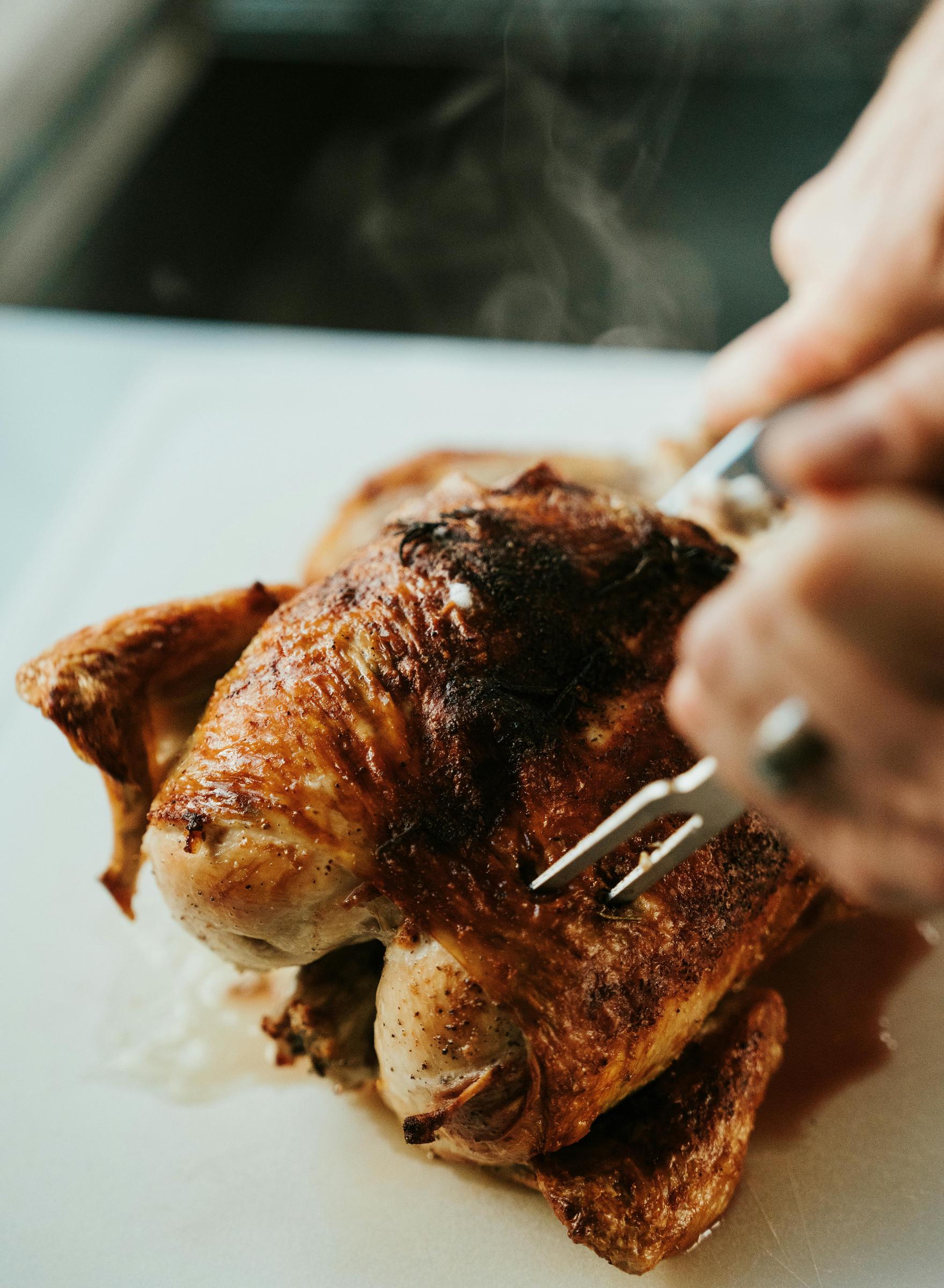 Un morceau de poulet rôti en train d'être découpé | Source : Pexels