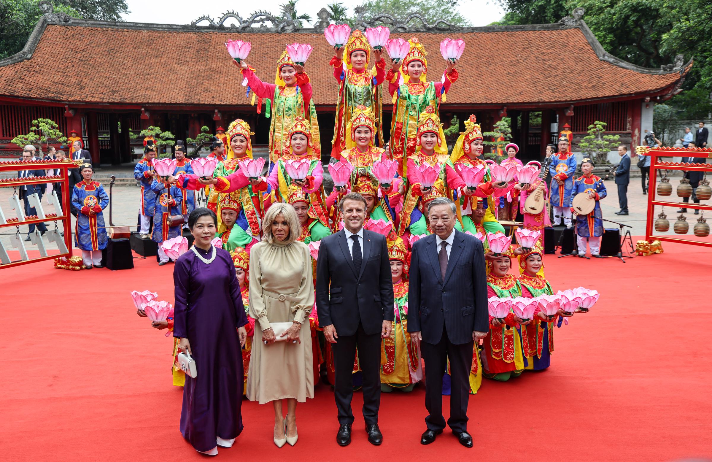 Le président français Emmanuel Macron (2e à droite), son épouse Brigitte Macron (2e à gauche), le secrétaire général du Parti communiste vietnamien To Lam (à droite) et son épouse Ngo Phuong Ly (à gauche) posent pour une photo avec des artistes après avoir assisté à une cérémonie au Temple de la Littérature à Hanoï, le 26 mai 2025 I Source : Getty Images