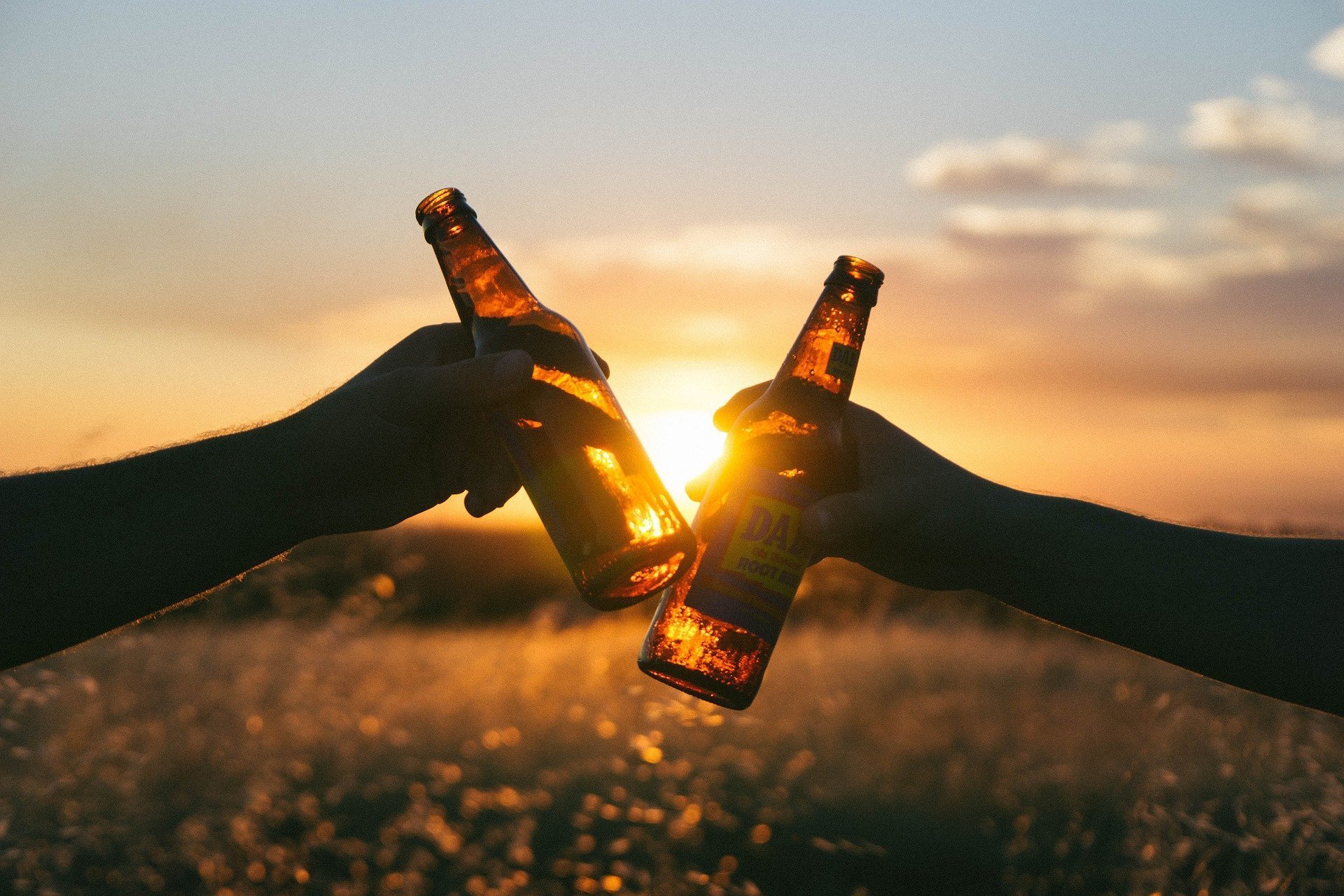 Bouteilles de bière clignotantes avec un coucher de soleil à l'arrière-plan. | Photo : Pixabay
