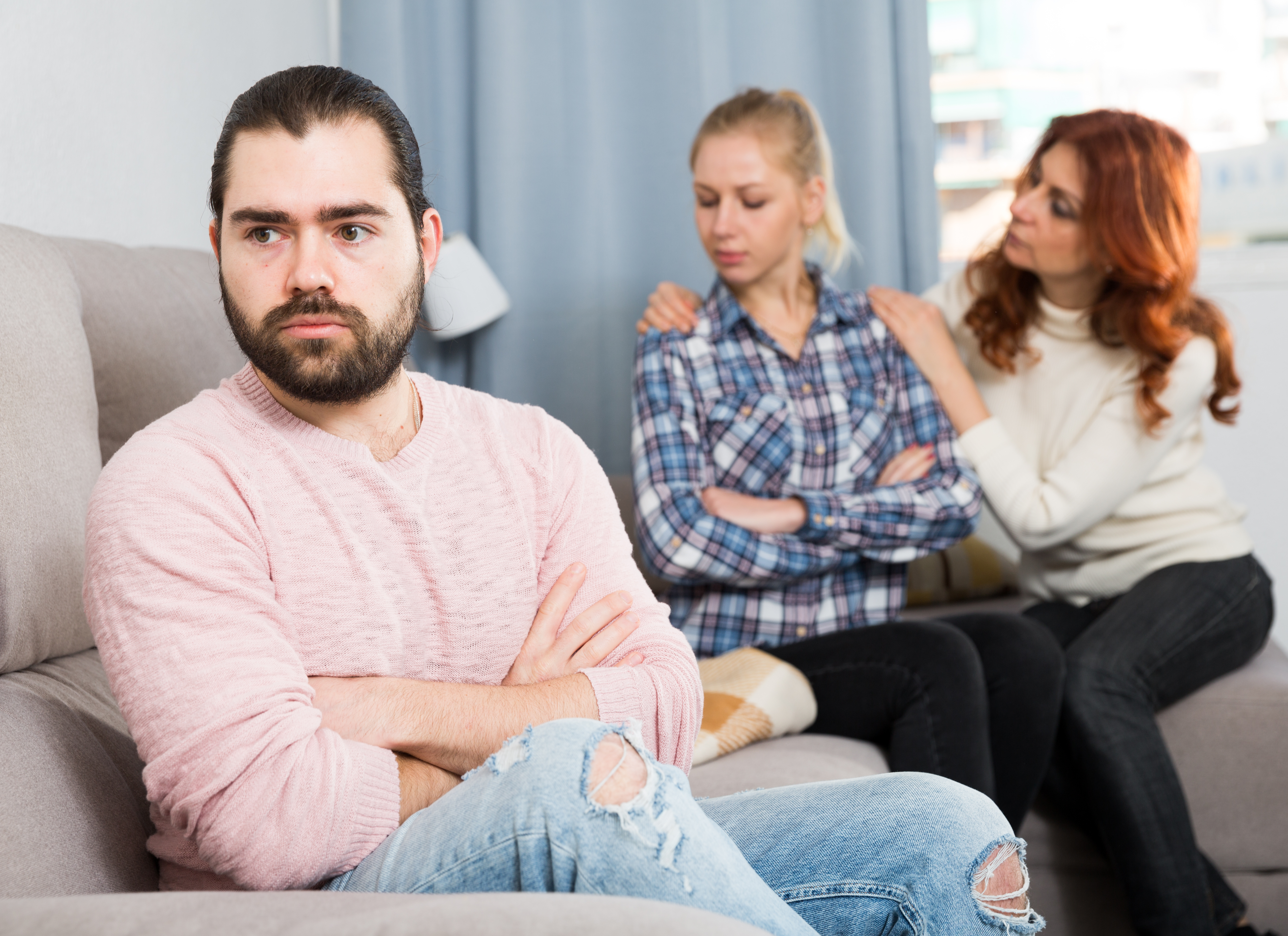 Une femme d'âge moyen réconforte une jeune fille tandis que son fils semble en colère et mécontent | Source : Shutterstock