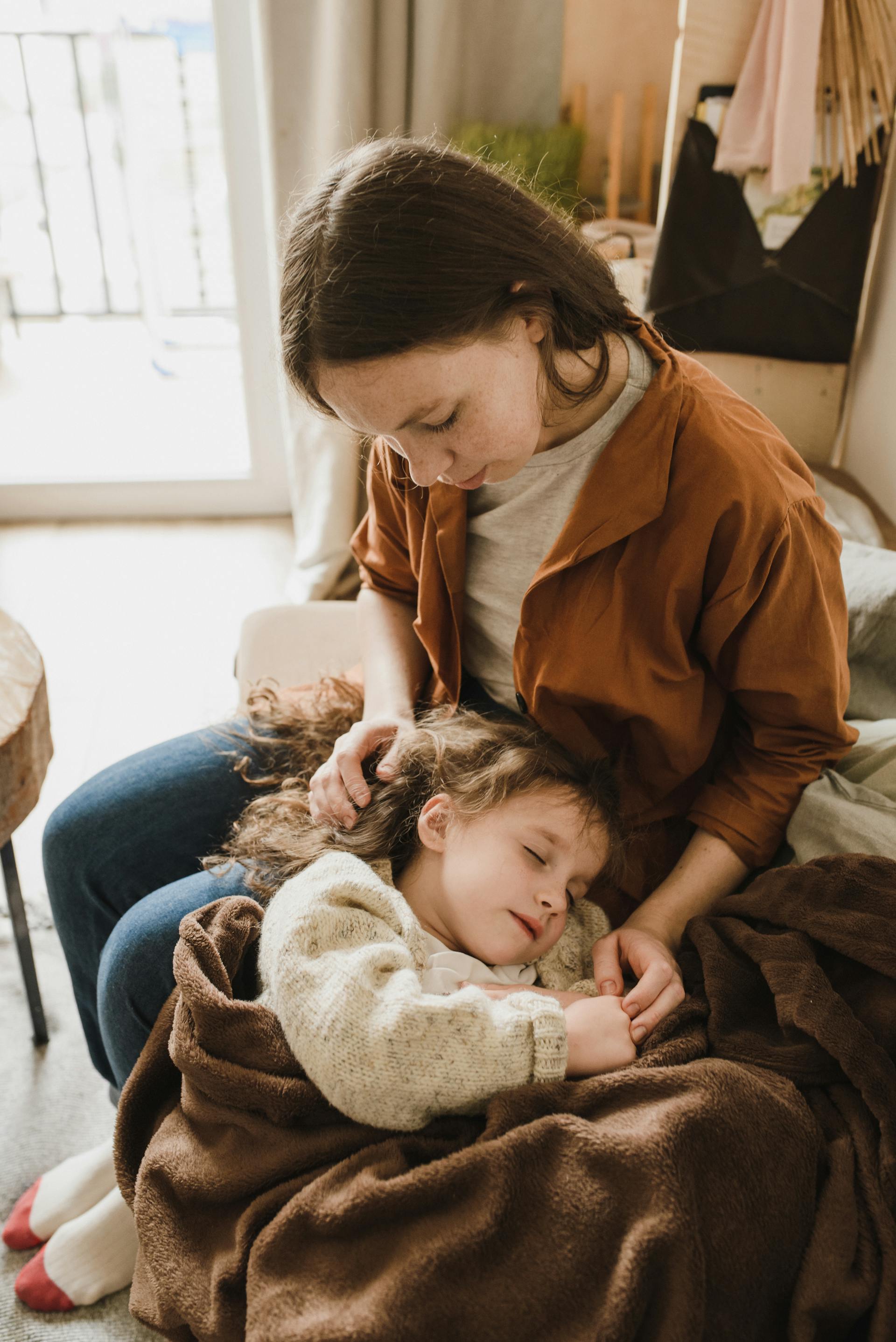 Une petite fille dormant sur les genoux de sa mère | Source : Pexels