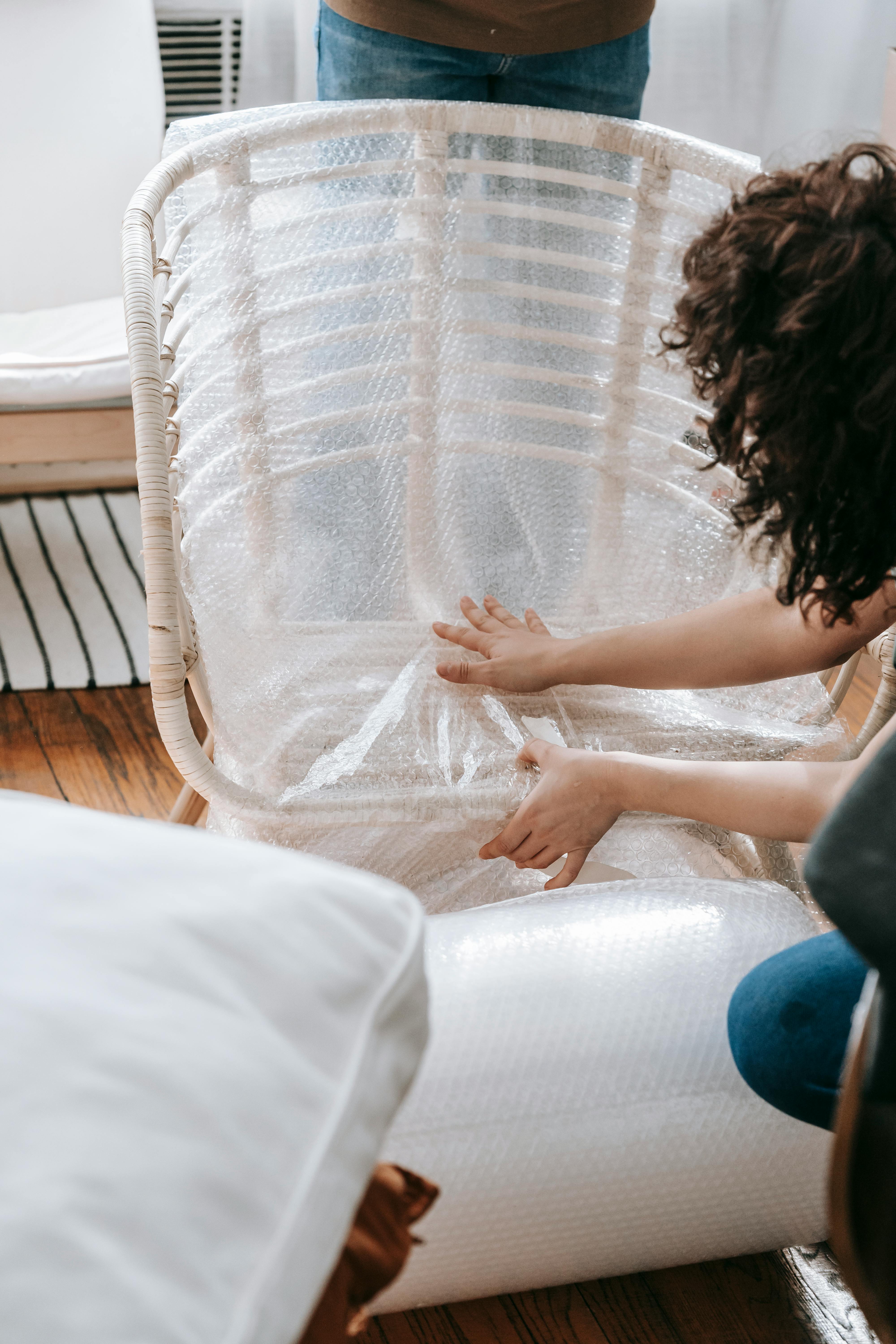 Une femme emballant une chaise dans du papier bulle | Source : Pexels