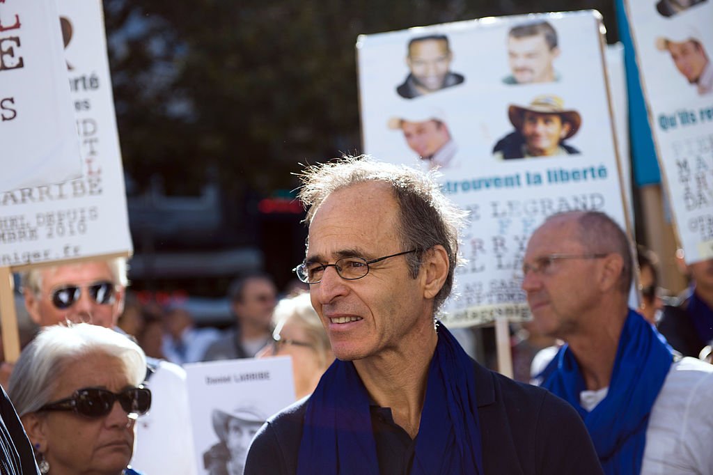 Le chanteur français Jean-Jacques Goldman (C) participe à une marche avec des manifestants à Marseille, dans le sud de la France, le 21 septembre 2013, pour demander la libération des quatre otages français enlevés en 2010 au Niger. | Photo : Getty Images