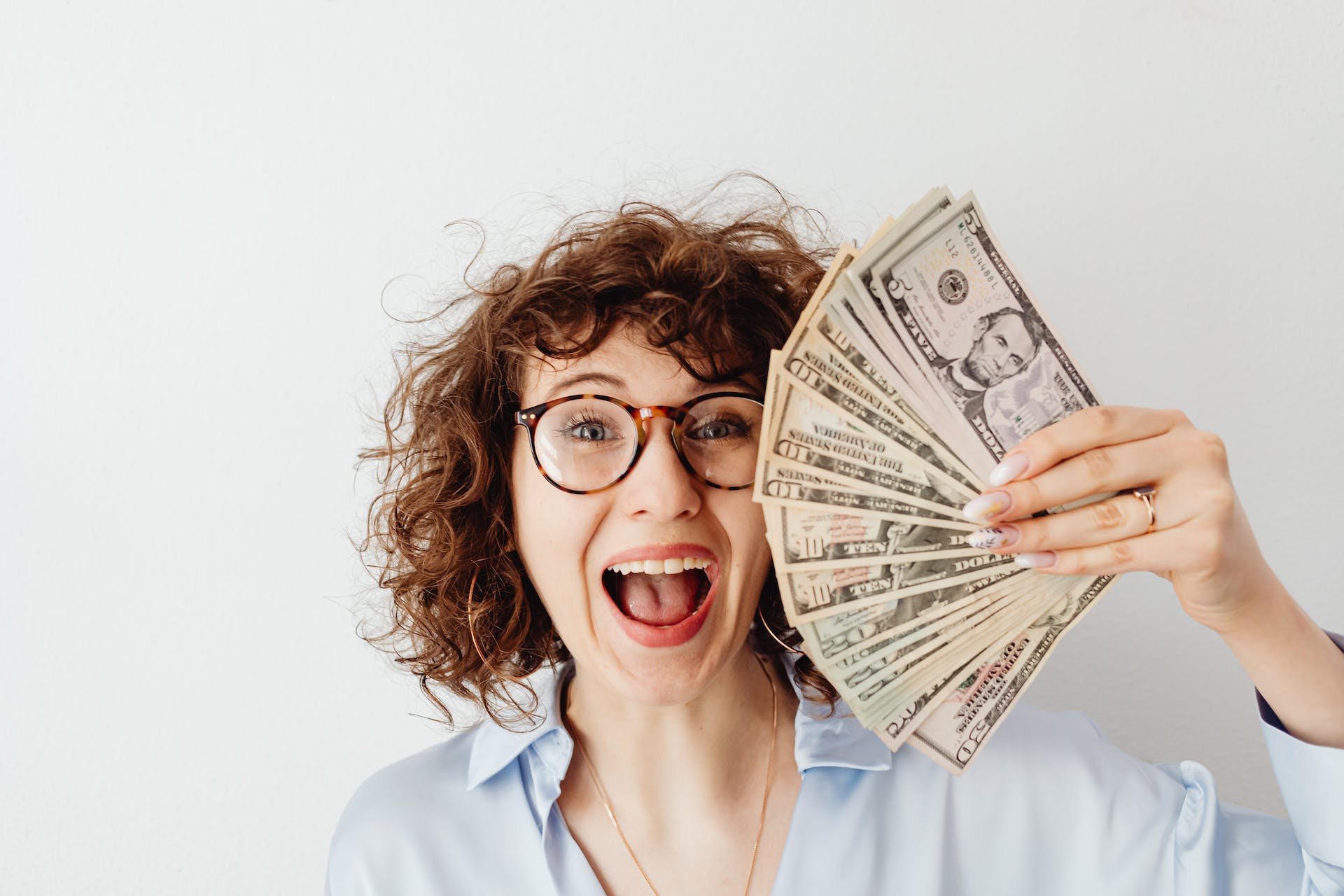 Une femme heureuse tenant des billets d'un dollar | Source : Pexels