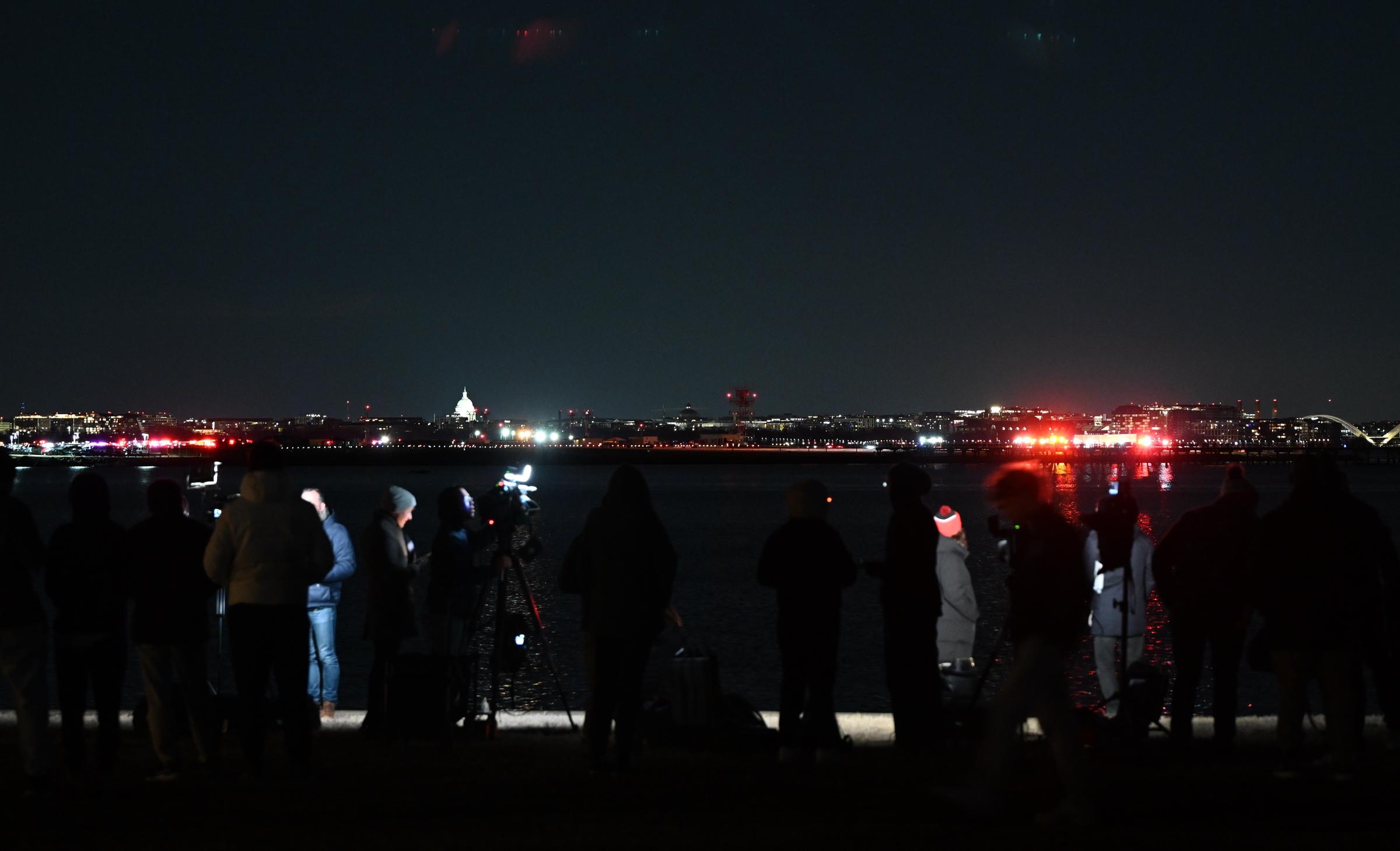 Des membres de la presse travaillent près de la zone de la scène après qu'un avion régional est entré en collision en plein vol avec un hélicoptère militaire et s'est écrasé dans la rivière Potomac à Washington, D.C., le 30 janvier 2025 | Source : Getty Images