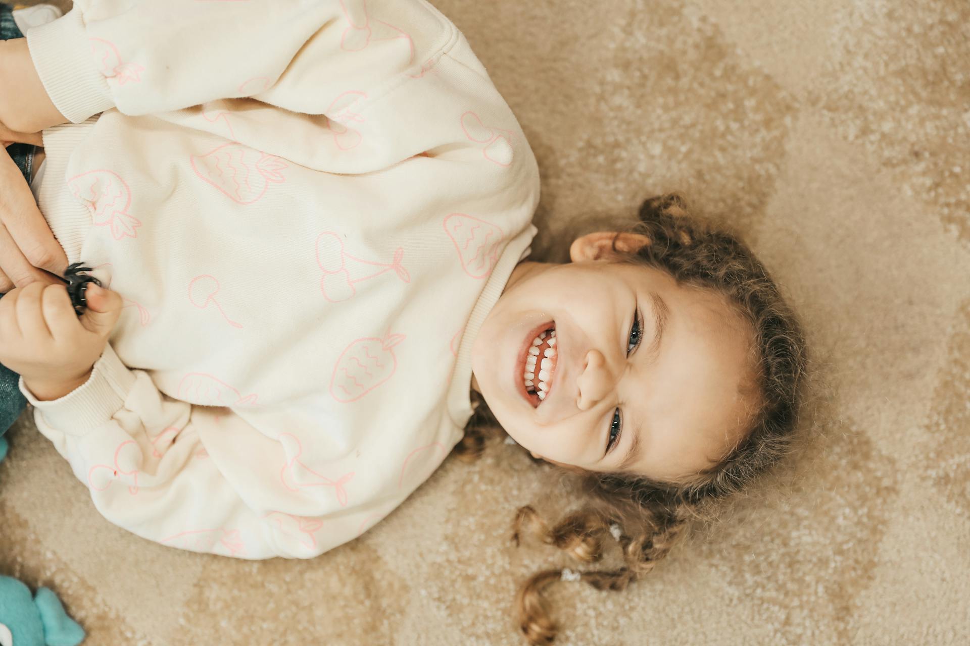 Un enfant souriant allongé sur le sol | Source : Pexels
