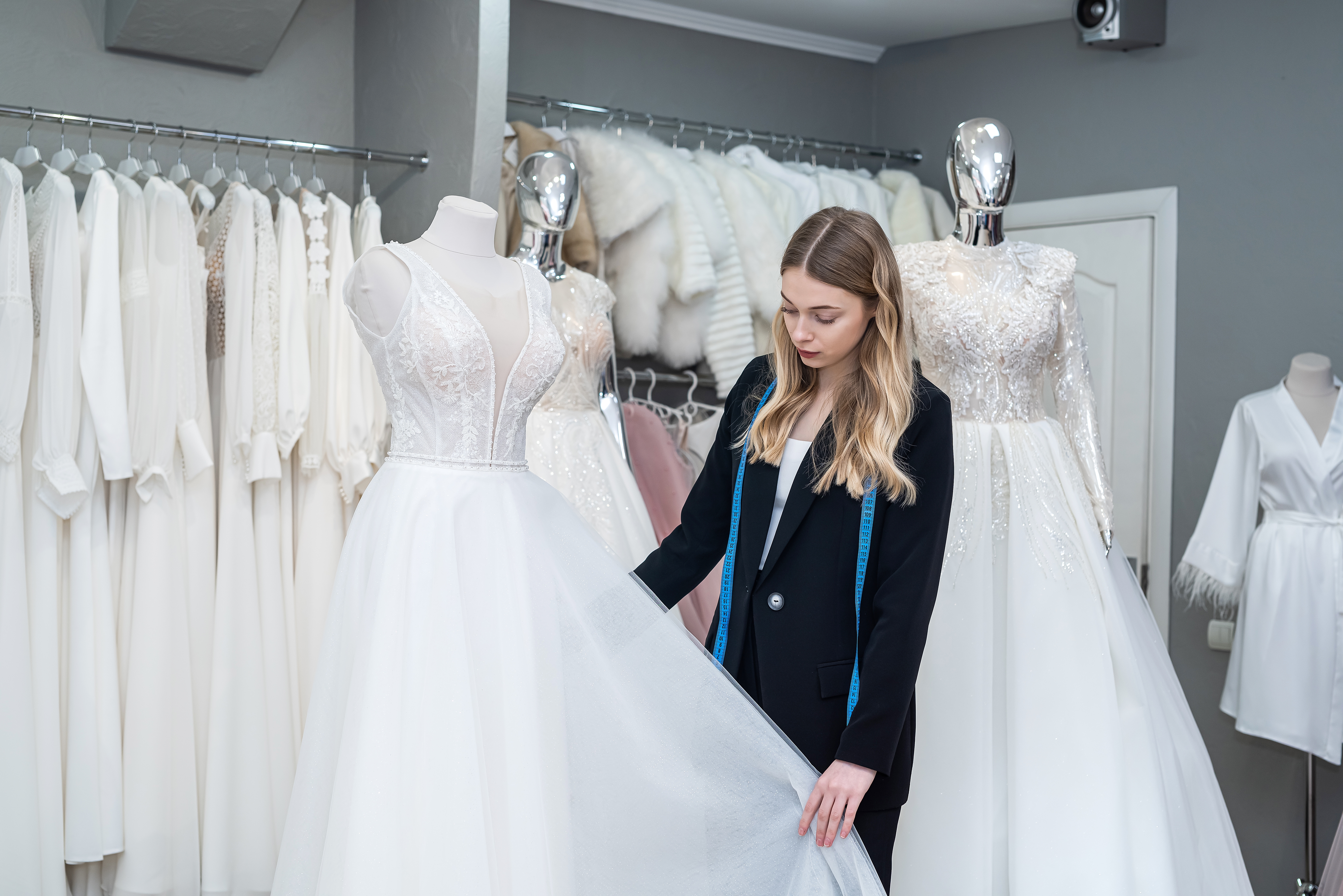 Une styliste prend les mesures d'une robe de mariée | Source : Shutterstock