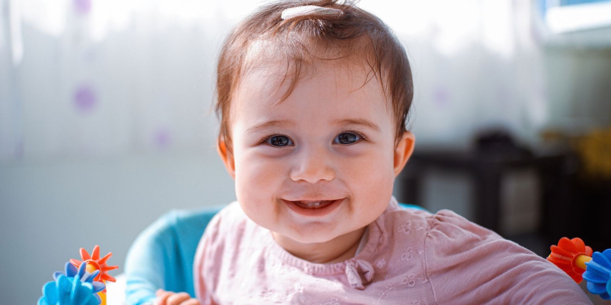 Une petite fille souriante assise dans un siège d'éveil coloré | Source : Pexels