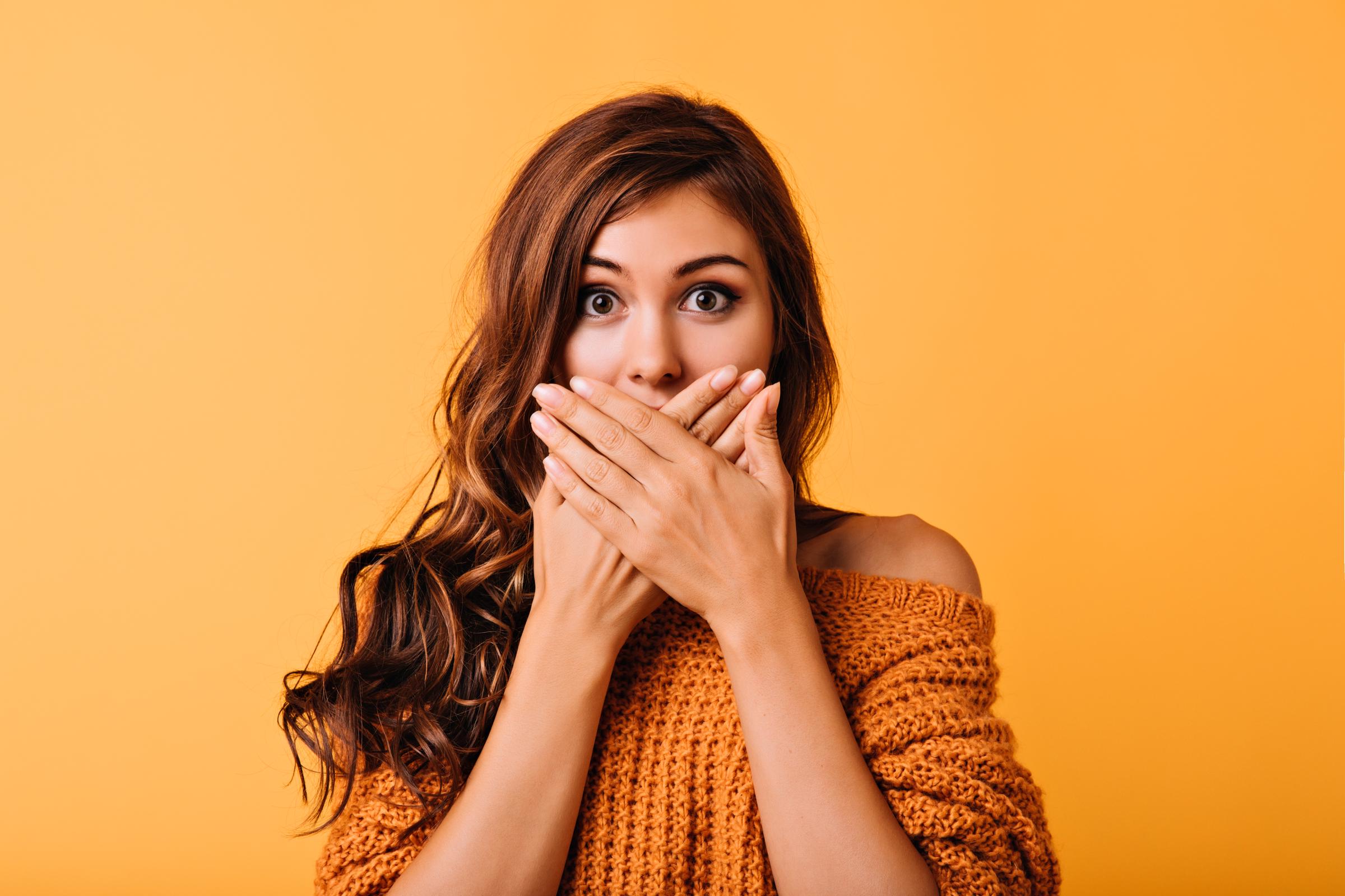 Une jeune femme surprise se couvrant la bouche. | Source : Freepik