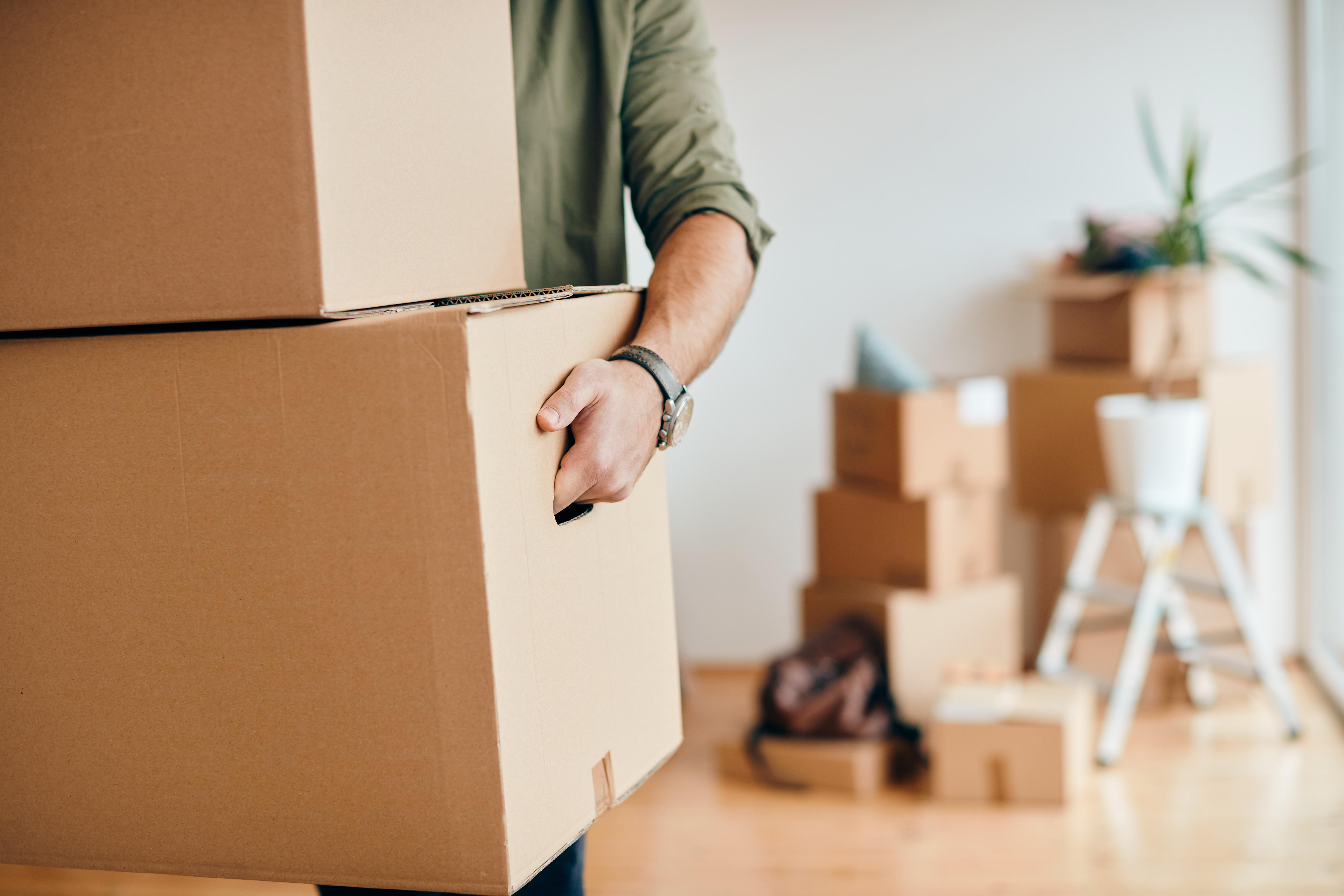 Gros plan d'un homme avec des cartons qui déménage dans une nouvelle maison | Source : Shutterstock