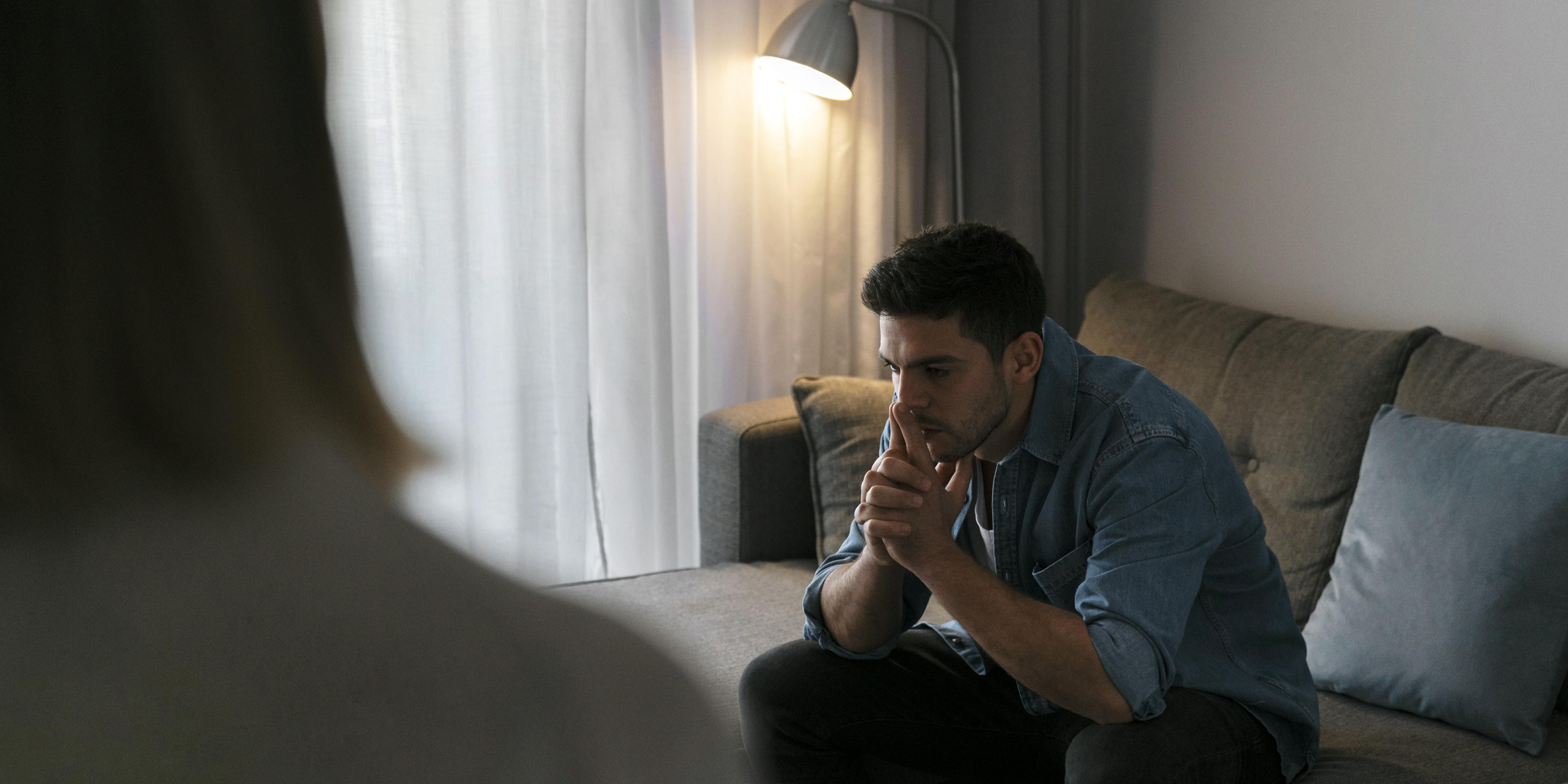 Un homme émotif assis sur un canapé | Source : Freepik