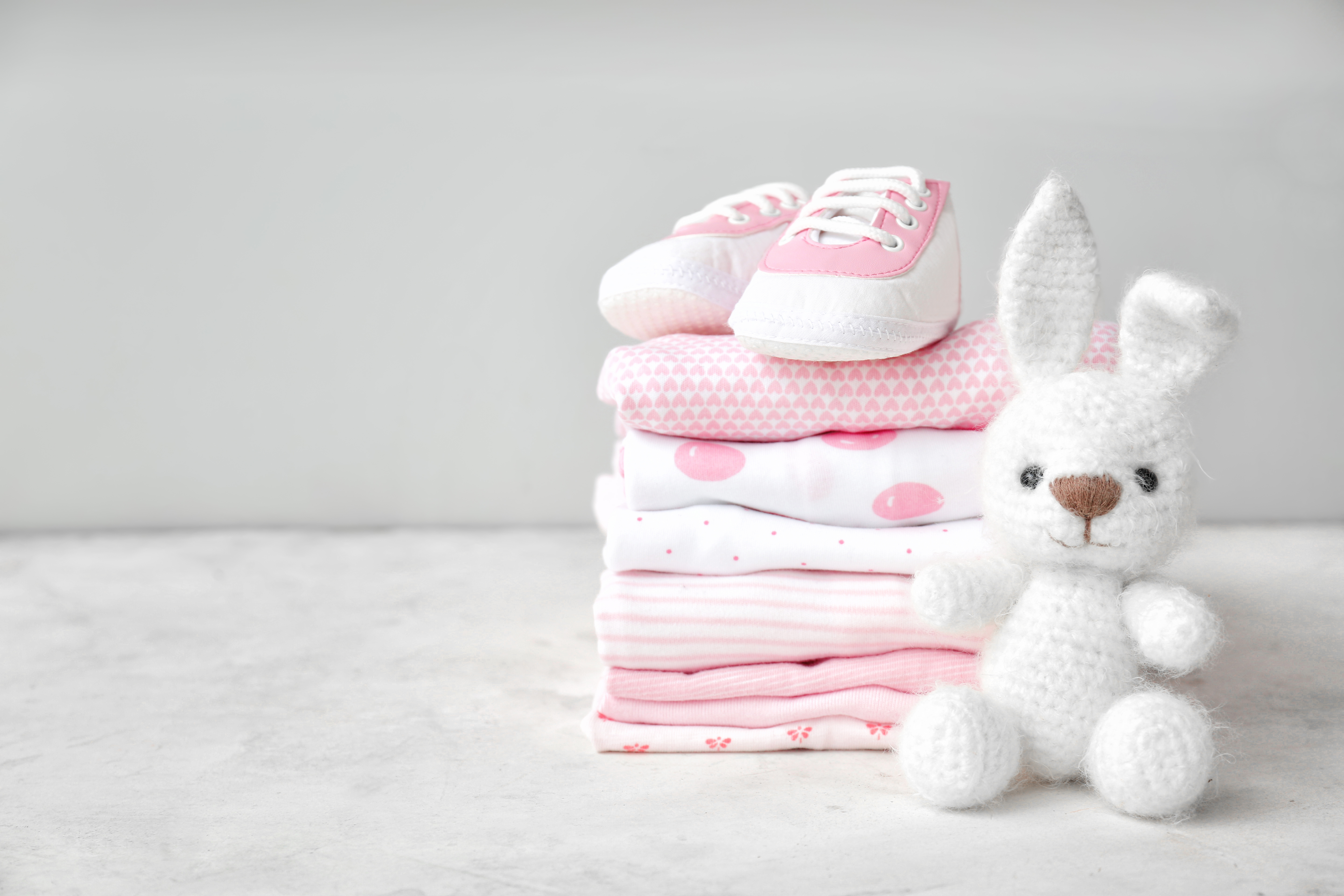 Une pile de vêtements de bébé, des chaussures et un jouet posés sur une table | Source : Shutterstock