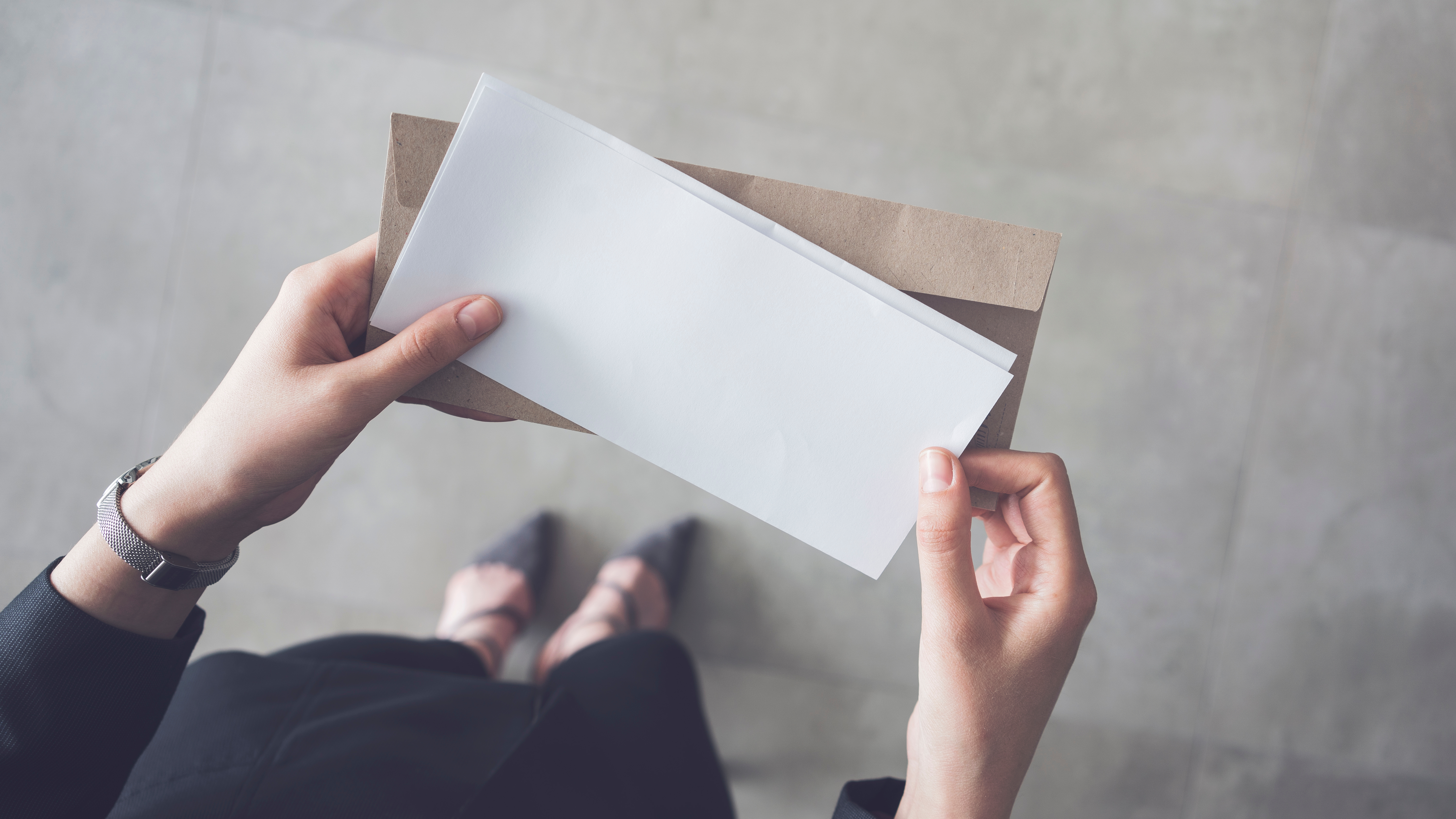 Une femme tenant un document et une enveloppe brune. | Source : Shutterstock/sebra