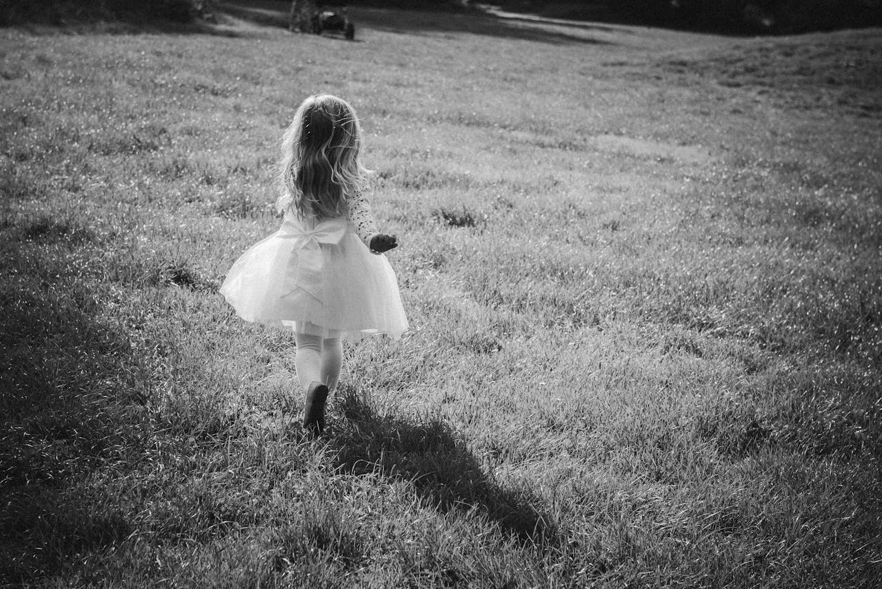 Photo en niveaux de gris d'une petite fille qui s'enfuit | Source : Pexels