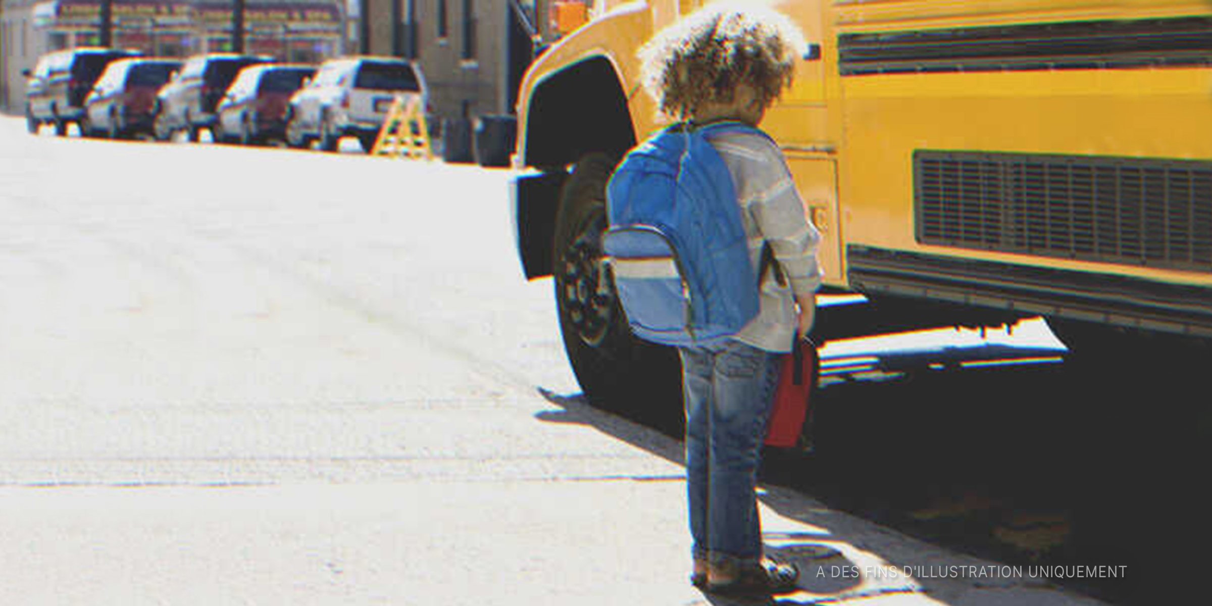 Un petit garçon se tenant devant un bus scolaire | Photo : Getty Images