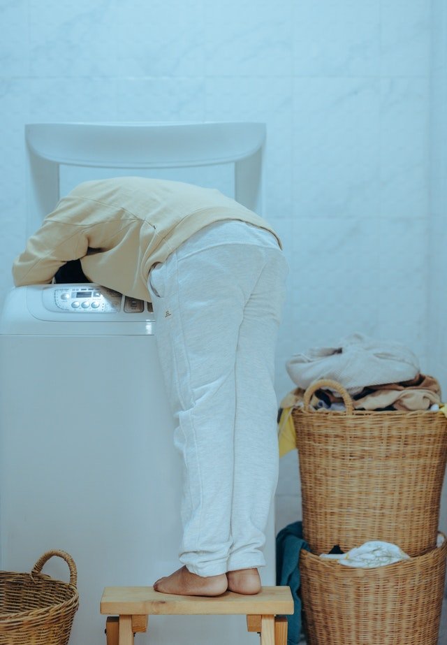 Un homme avec la tête dans la machine à laver | Photo : Pexels