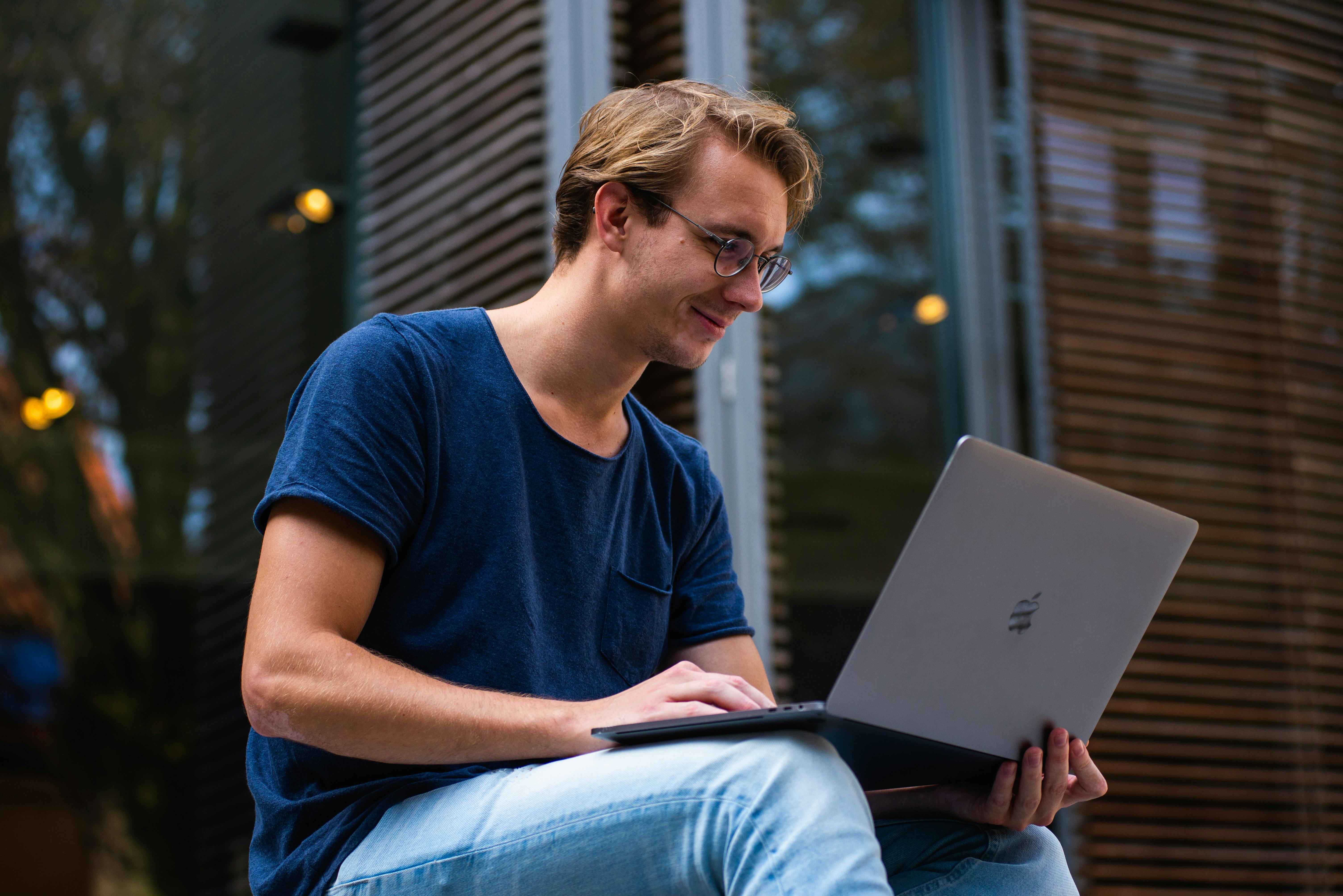 Un homme souriant avec un ordinateur portable | Source : Pexels