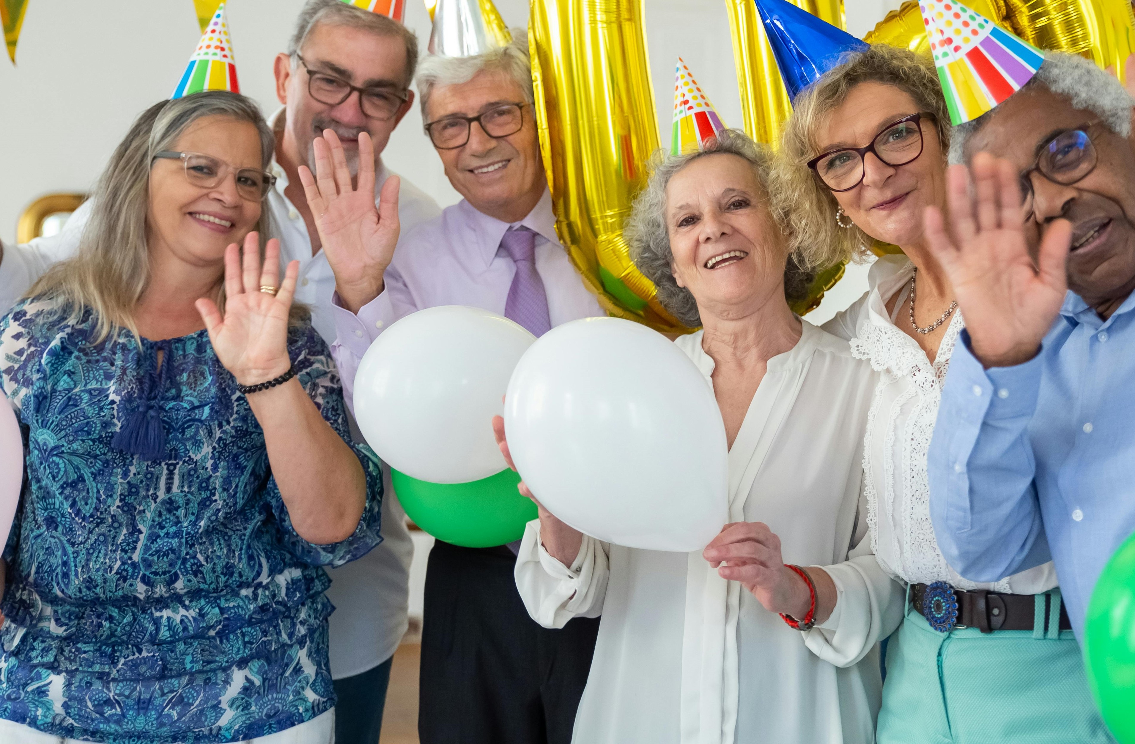 Des personnes portant des chapeaux de fête et tenant des ballons | Source : Pexels