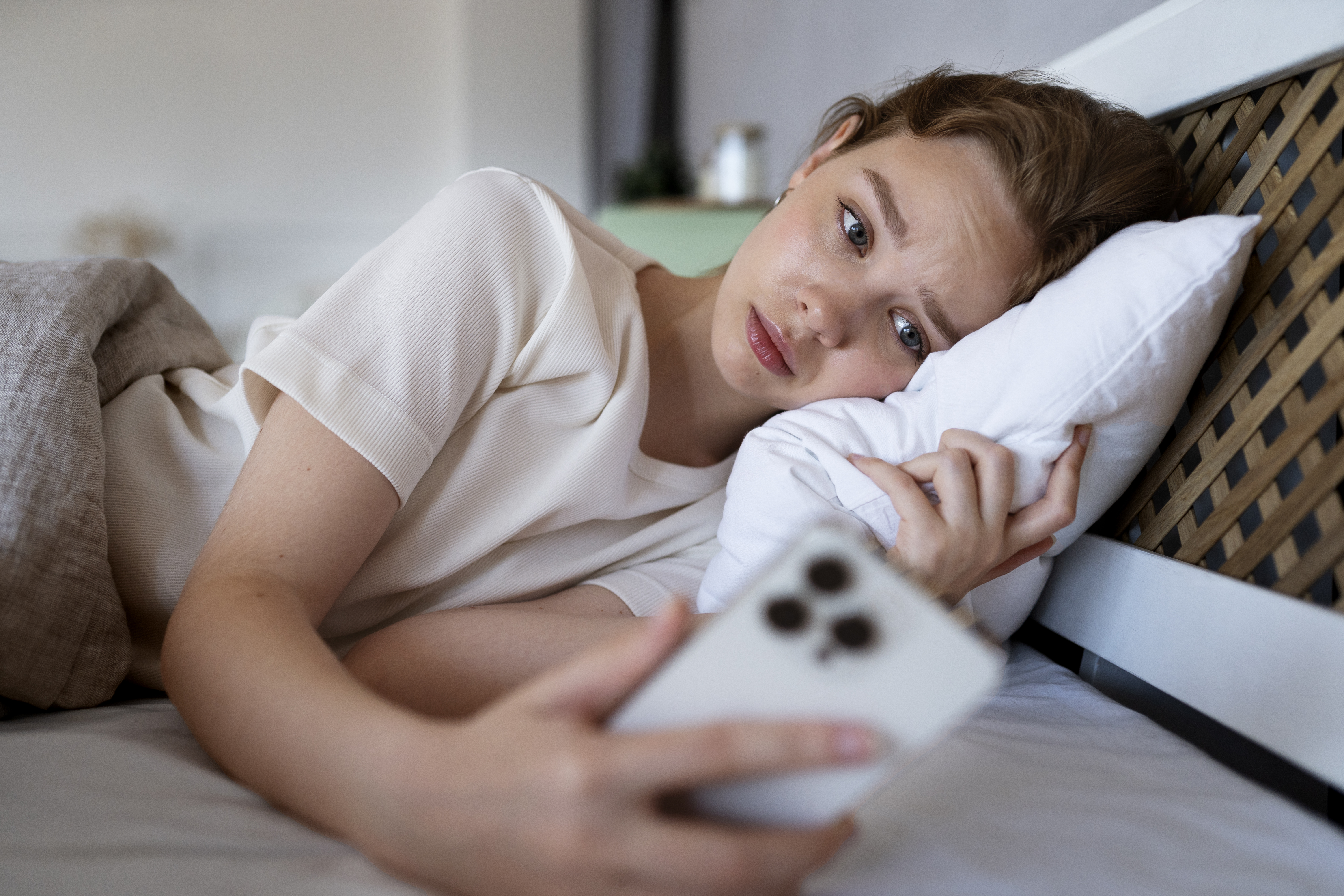 Une photo d'une jeune femme regardant anxieusement son téléphone | Source : Freepik