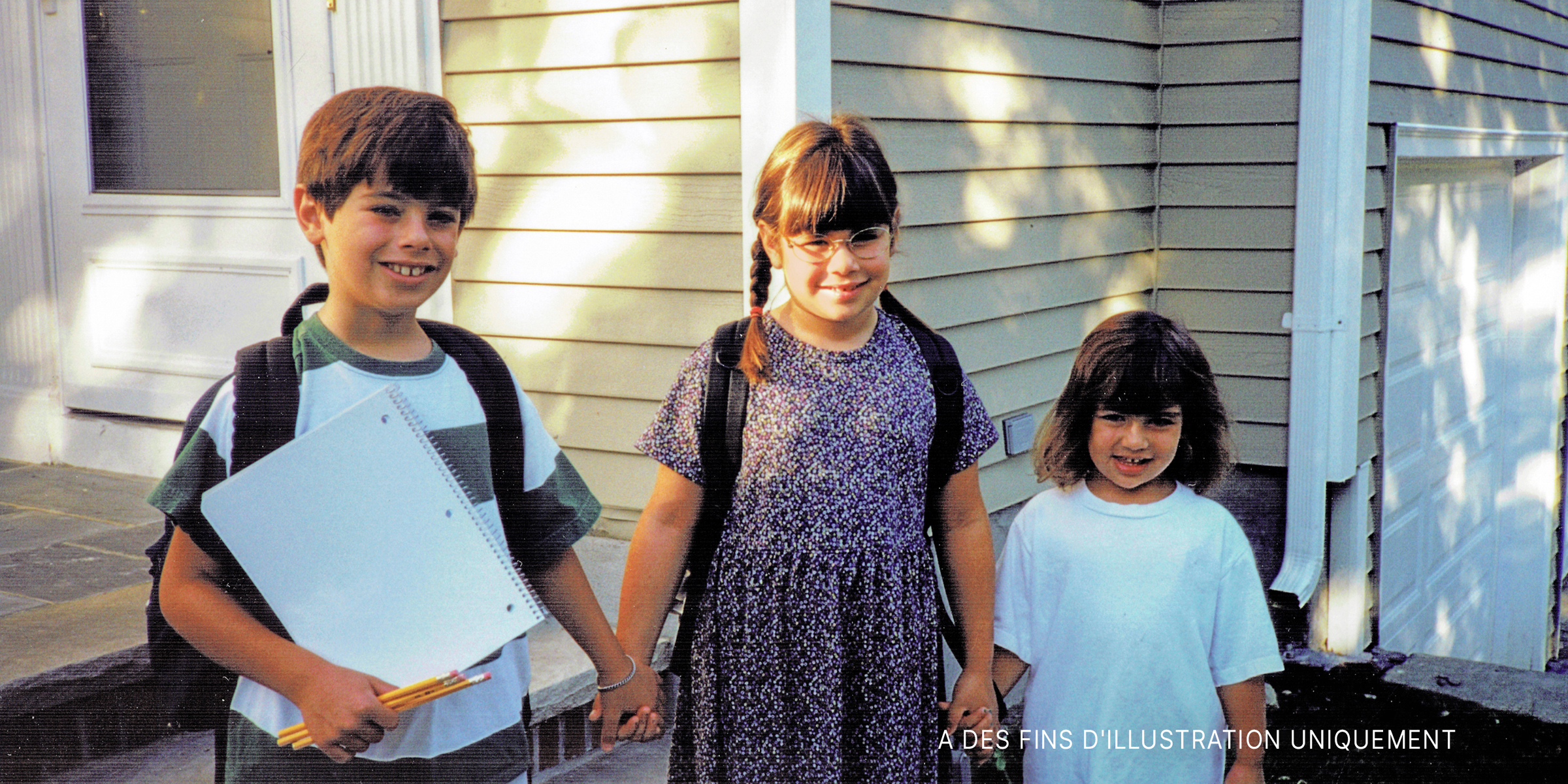 Trois enfants se tenant la main | Source : Shutterstock