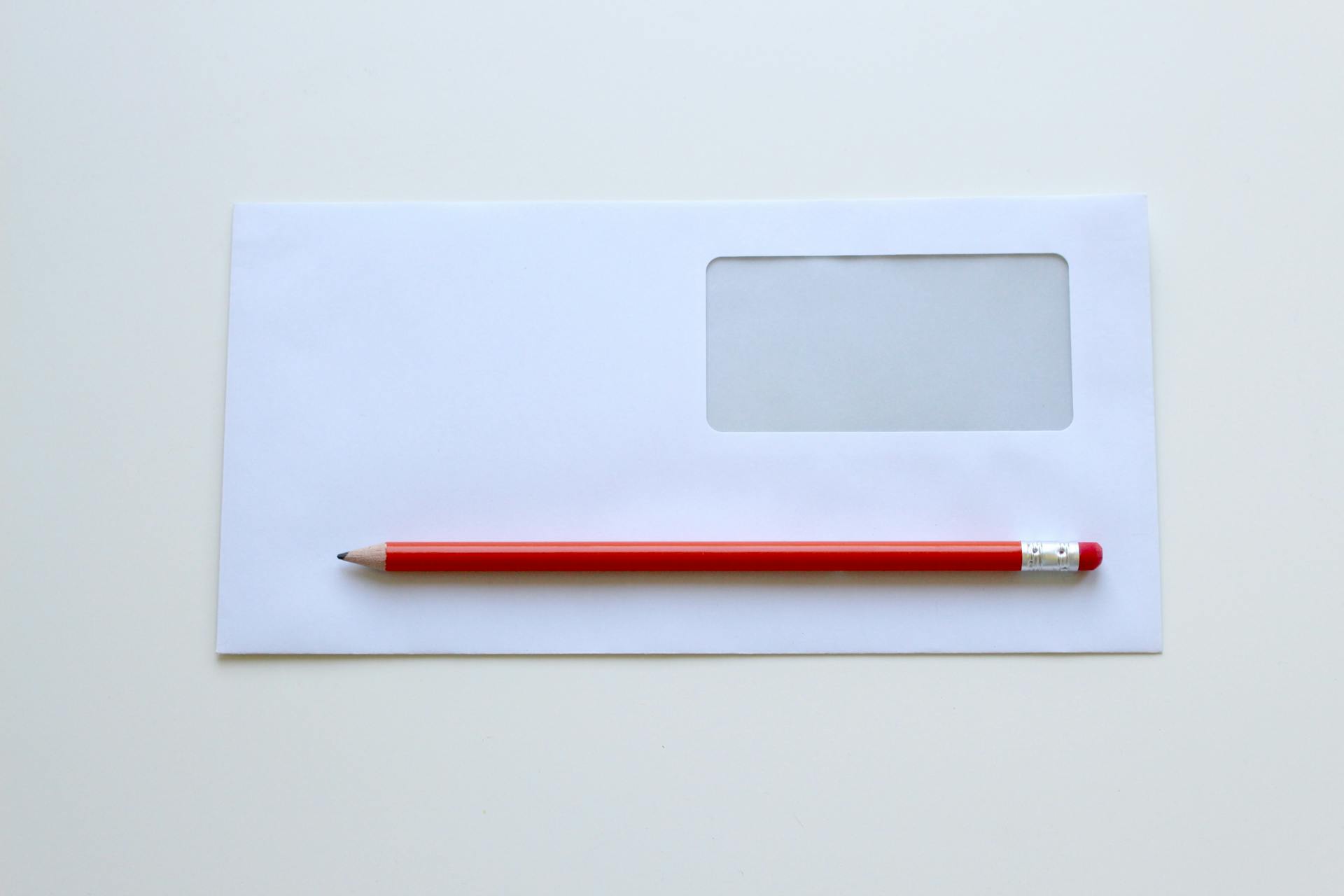 Un crayon rouge sur une enveloppe blanche à fenêtre | Source : Pexels