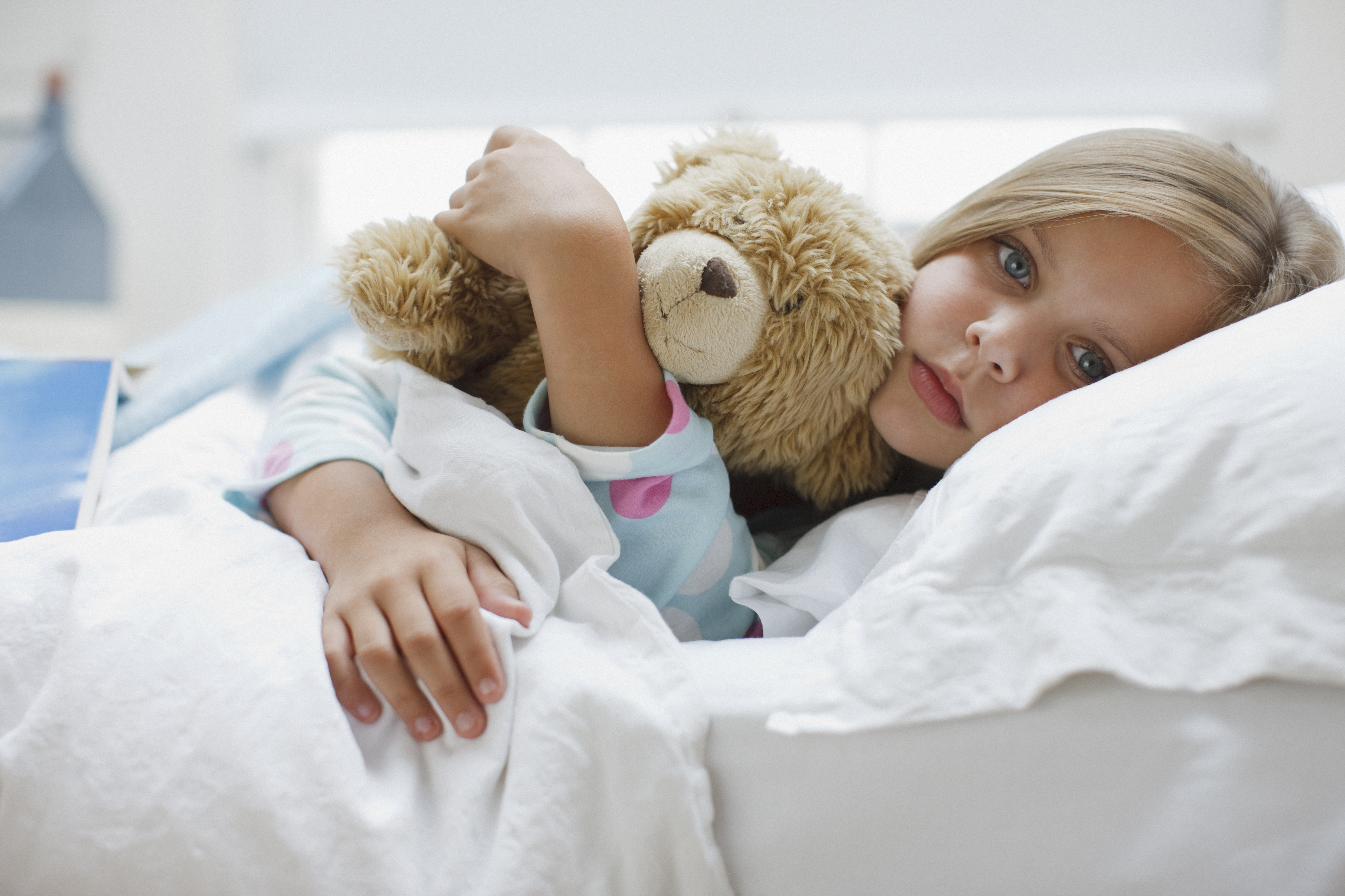 Une fille malade couchée dans son lit avec un ours en peluche | Source : Getty Images
