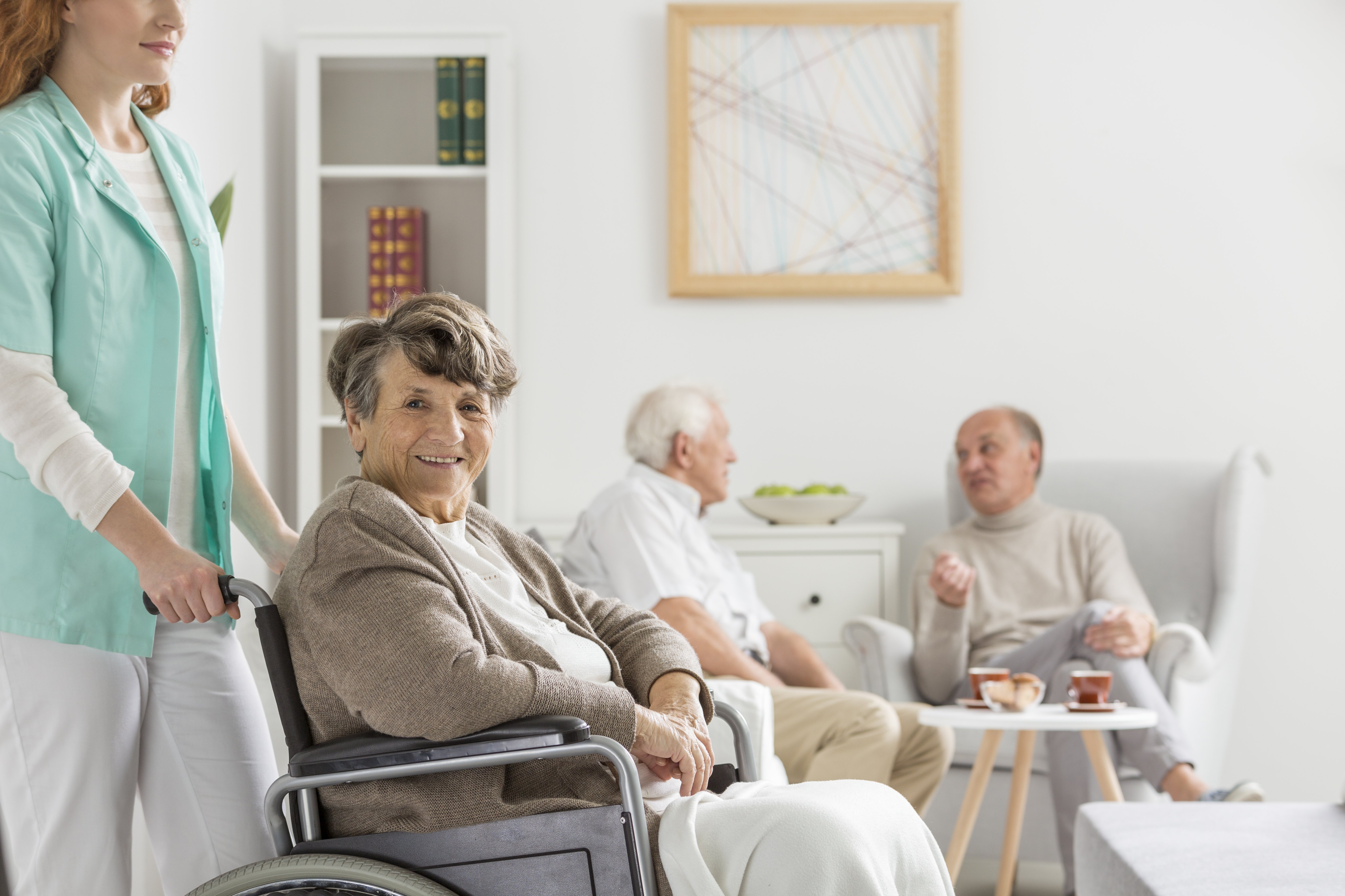 L'infirmière aide les personnes âgées heureuses en fauteuil roulant à déménager à la maison de retraite. | Photo : Shutterstock