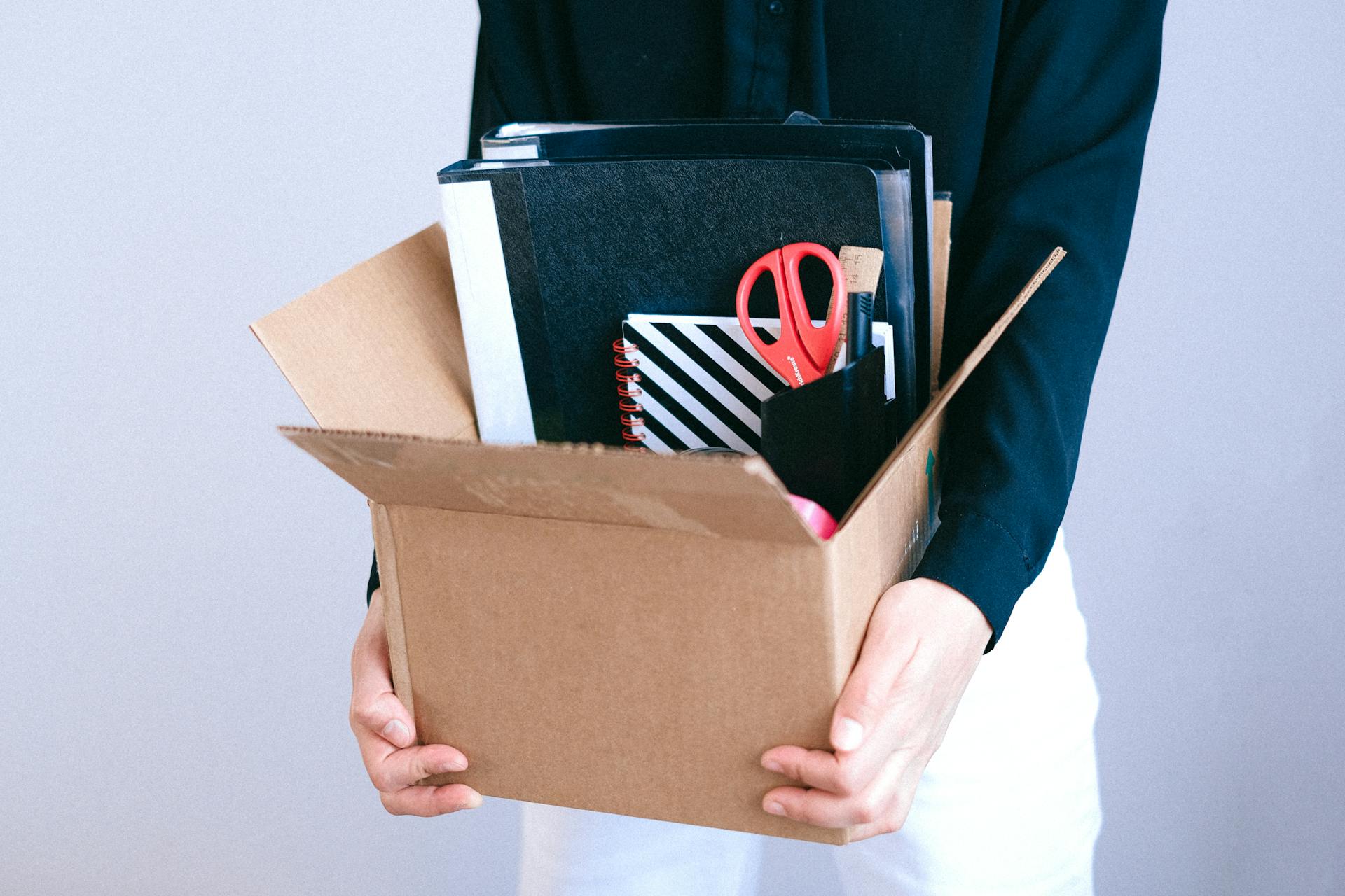 Une femme tenant un carton avec ses articles de bureau à l'intérieur | Source : Pexels