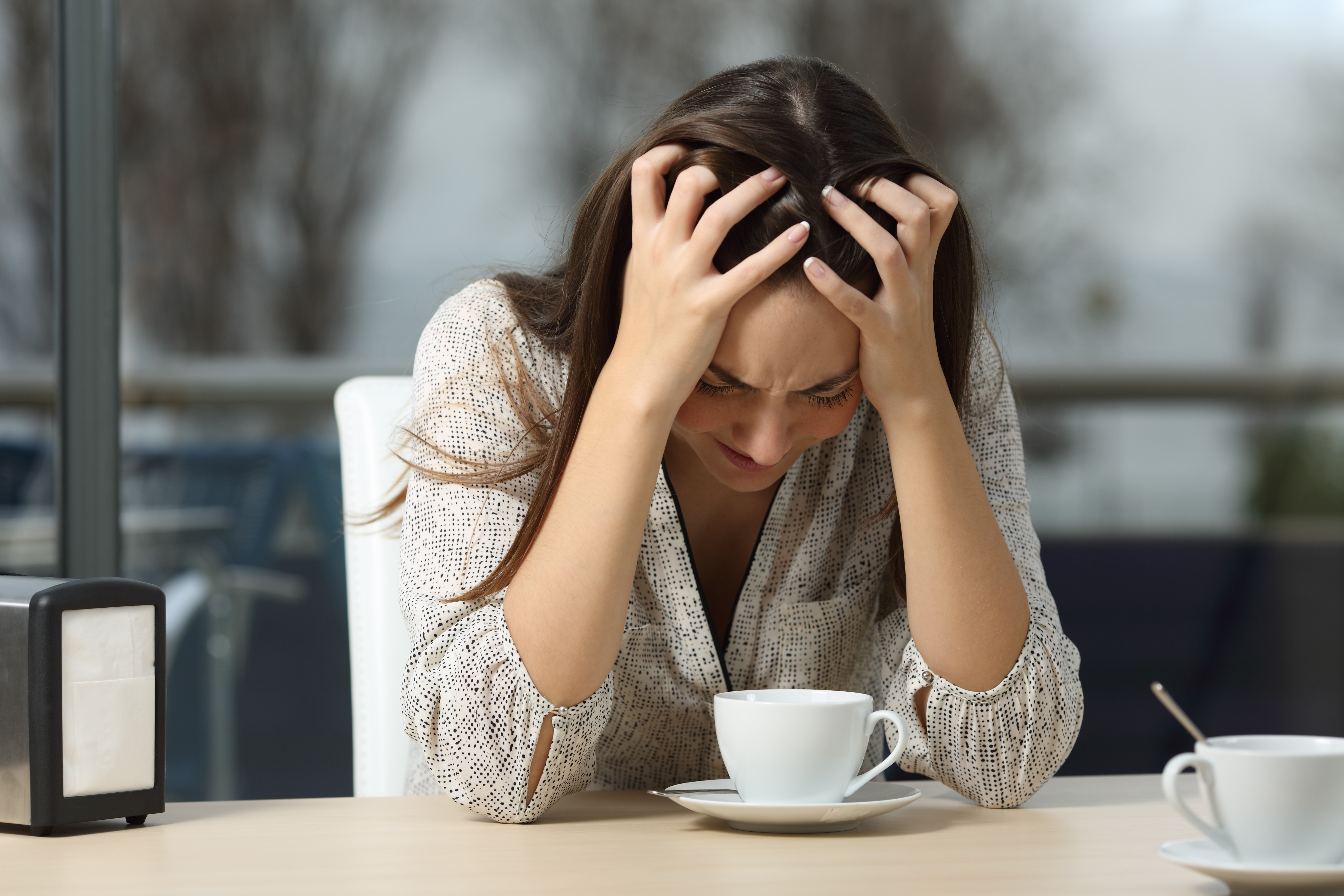 Femme déprimée assise seule dans un café | Source : Shutterstock