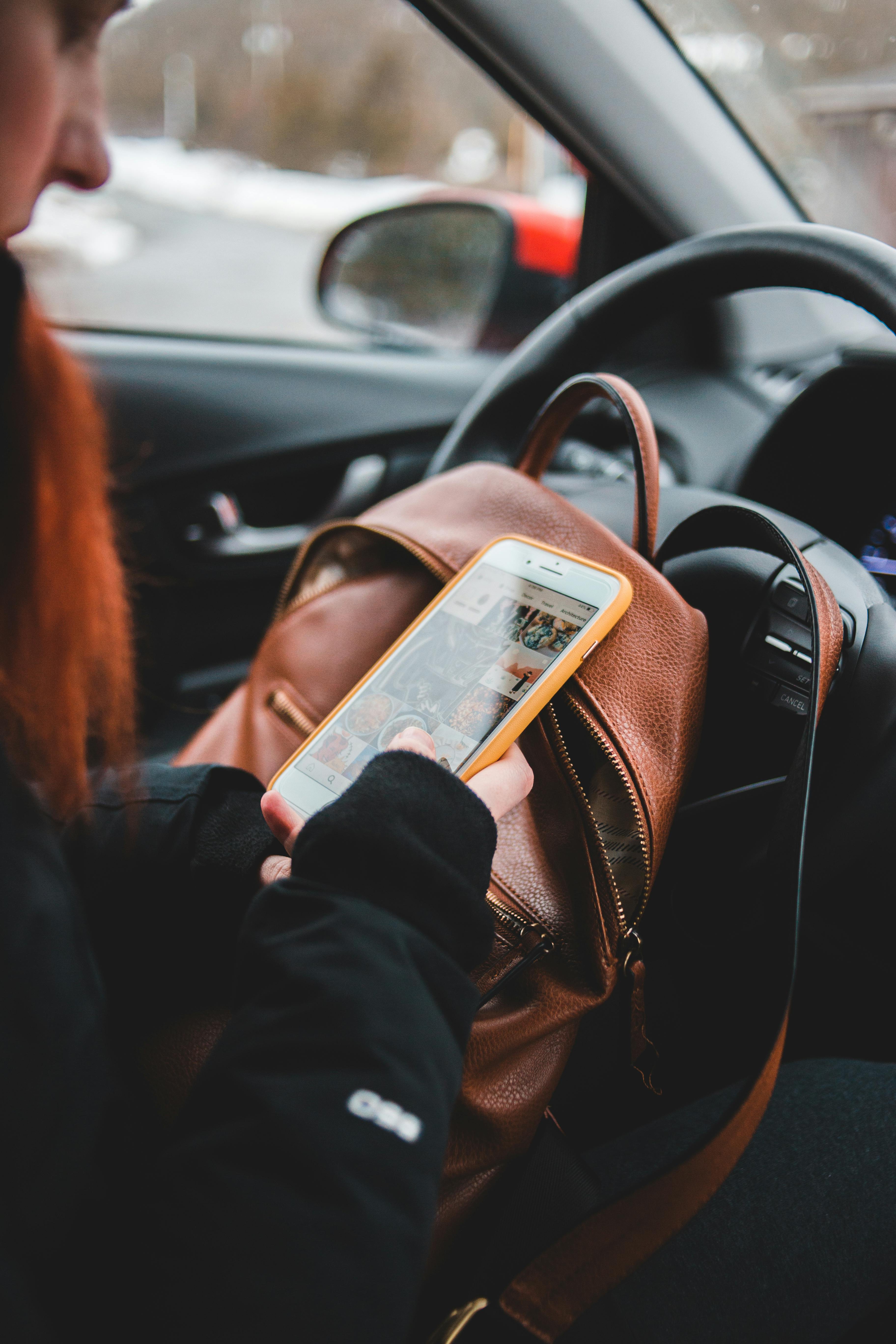 Une femme vérifie son téléphone depuis l'intérieur de la voiture | Source : Pexels