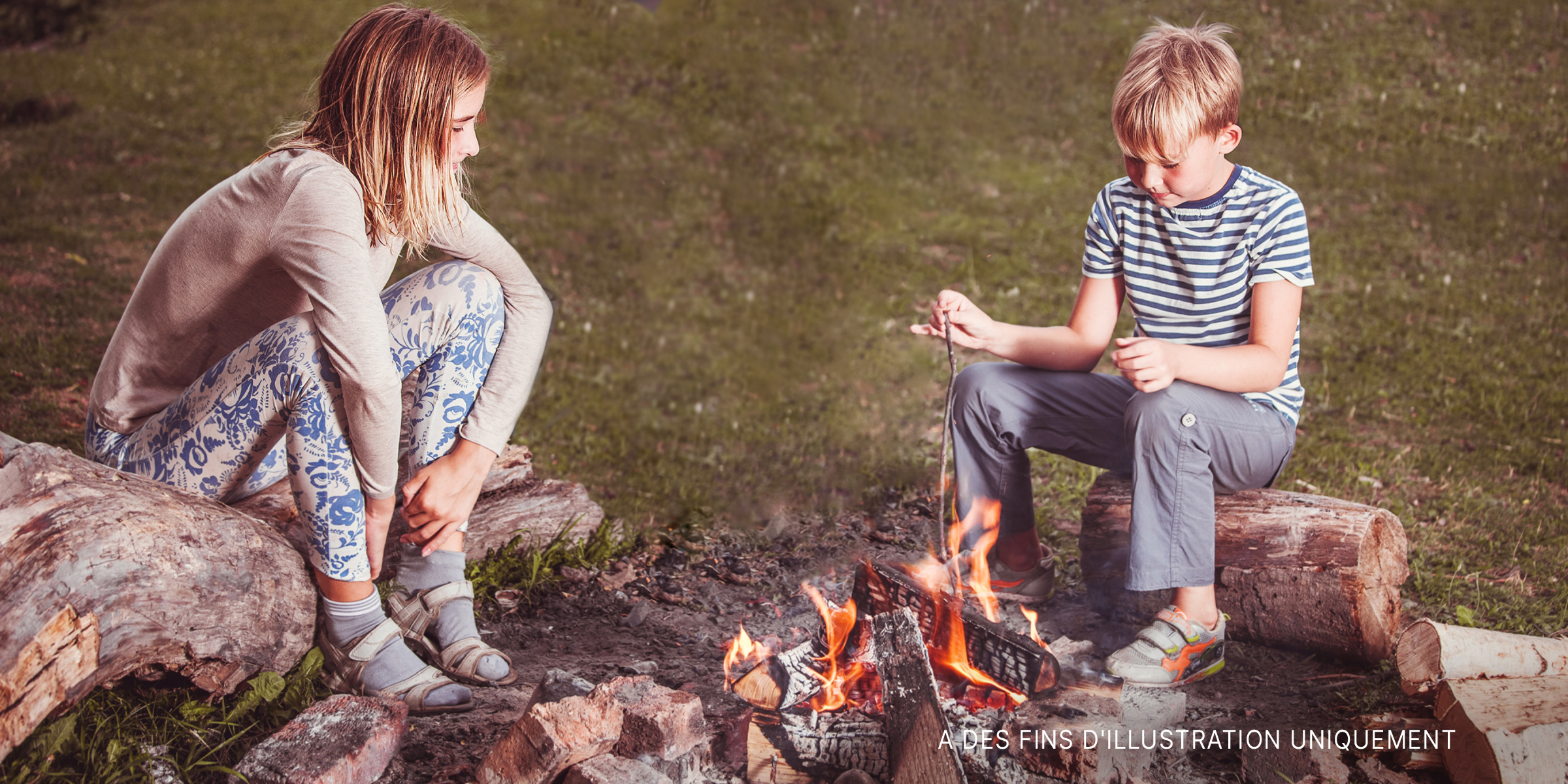 Un garçon et une fille assis l'un en face de l'autre à un feu de camp | Source : Shutterstock