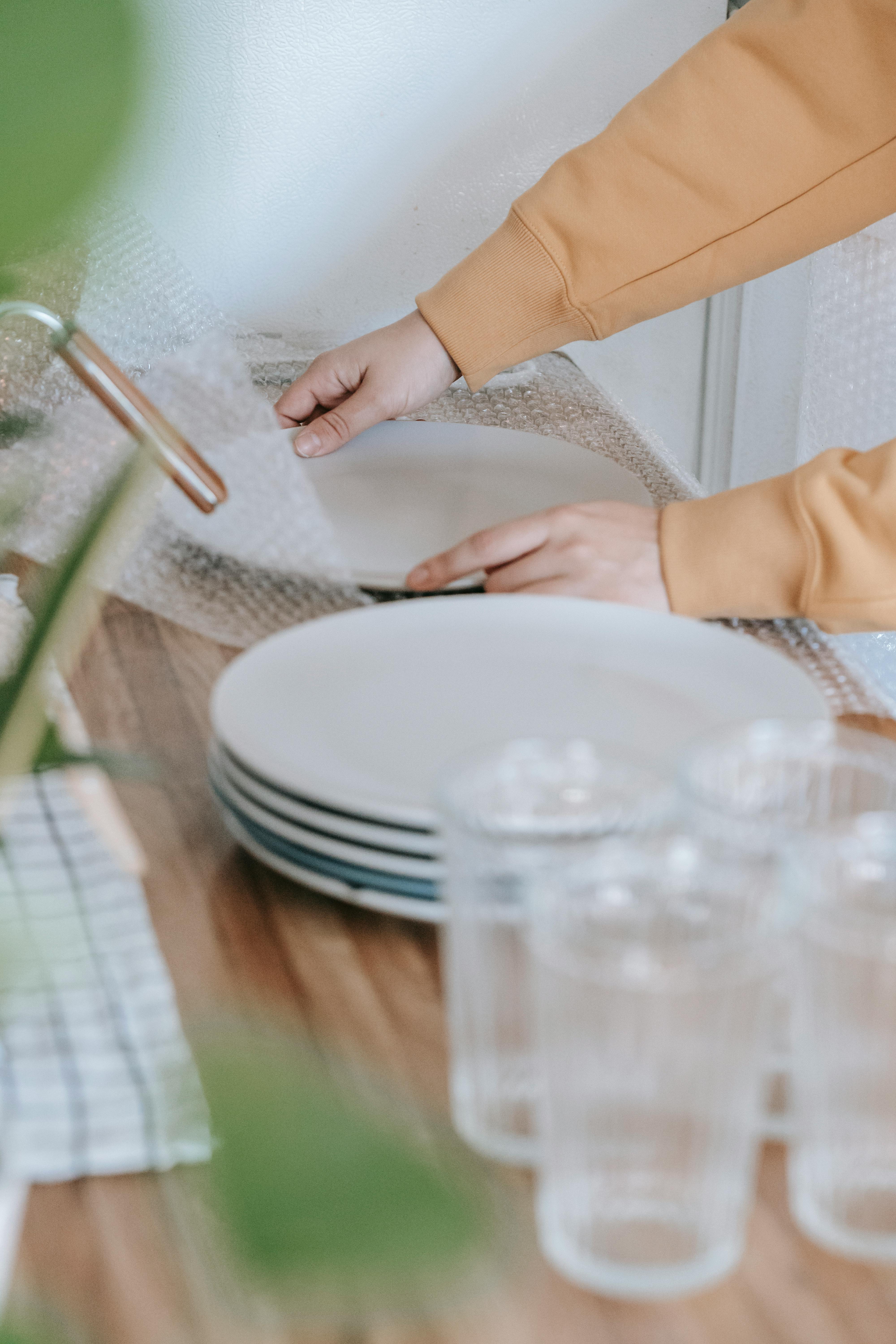 Une femme qui met du papier bulle sur des assiettes | Source : Pexels