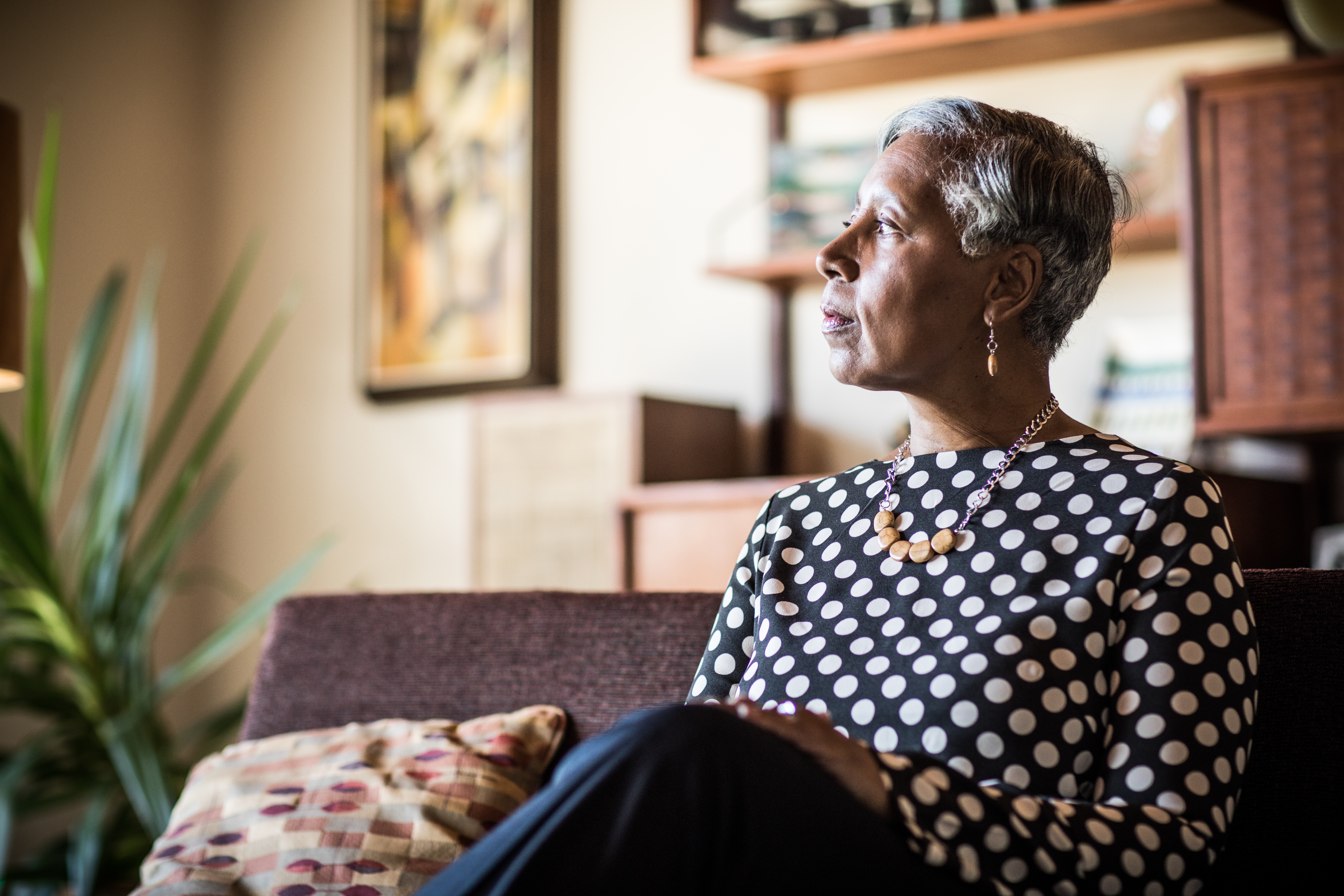 Portrait d'une femme (60 ans) assise sur le canapé à la maison | Source : Getty Images