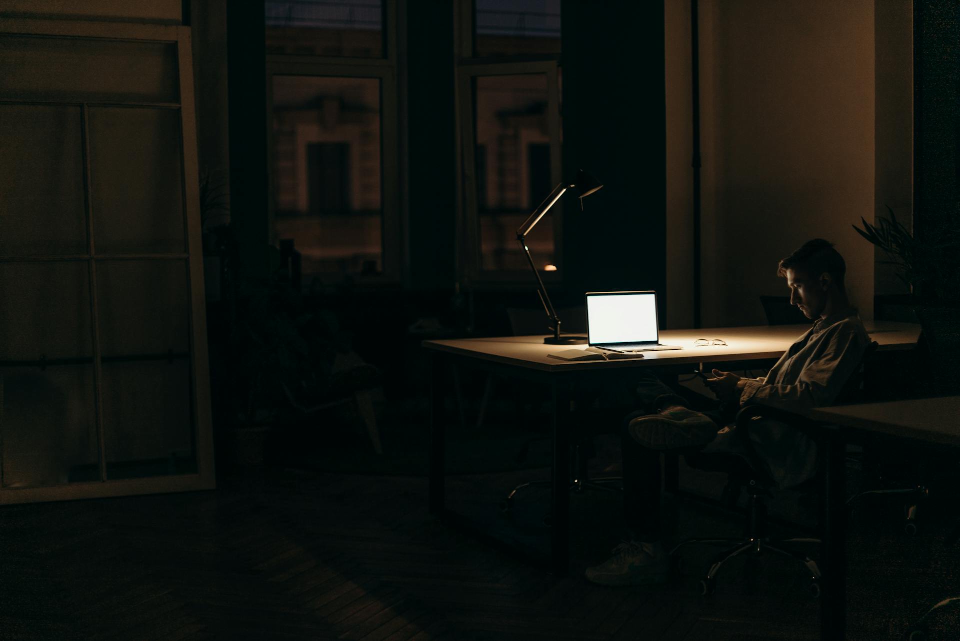 Un homme assis à un bureau dans une pièce sombre | Source : Pexels