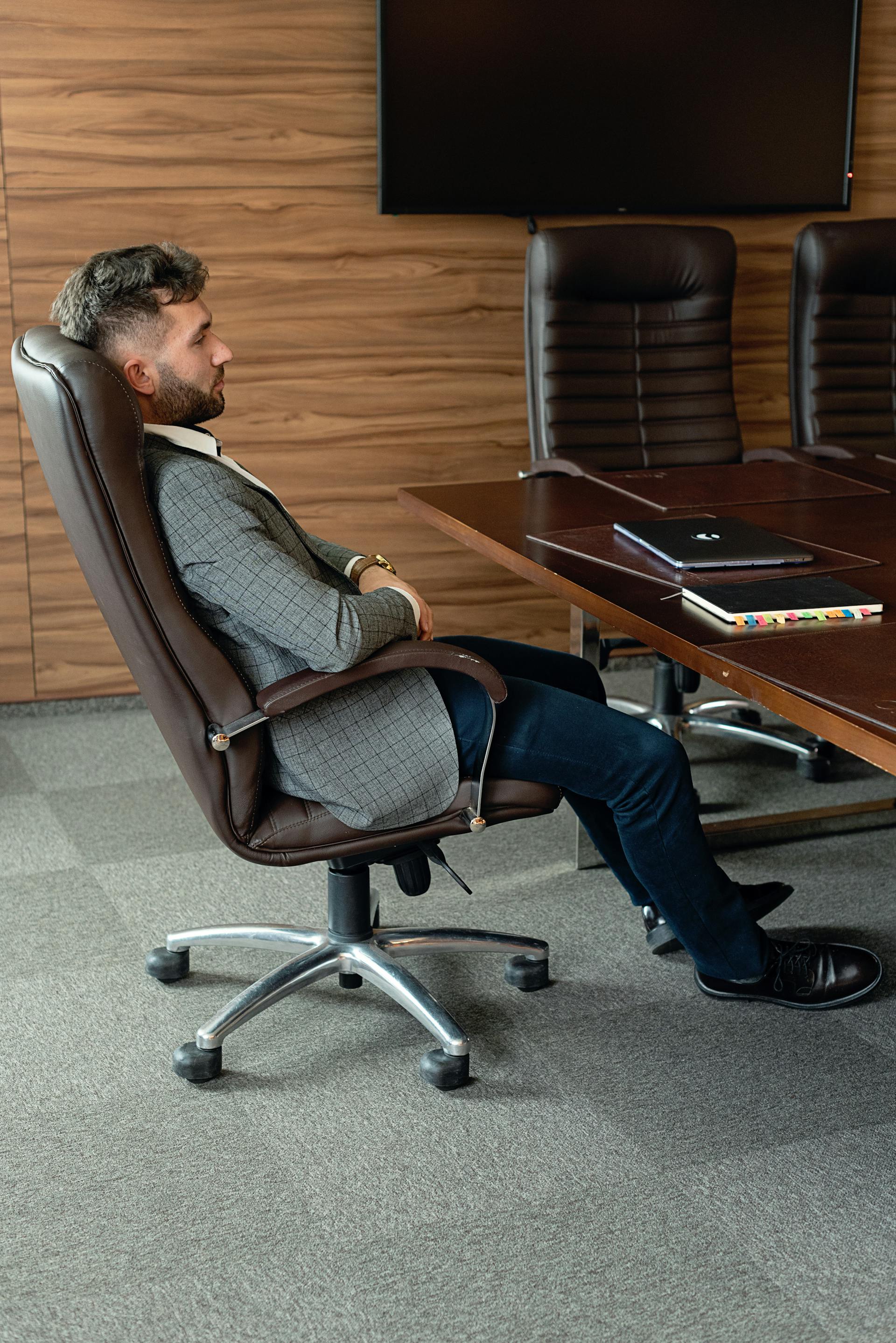 Vue latérale d'un homme adossé à sa chaise de bureau | Source : Pexels
